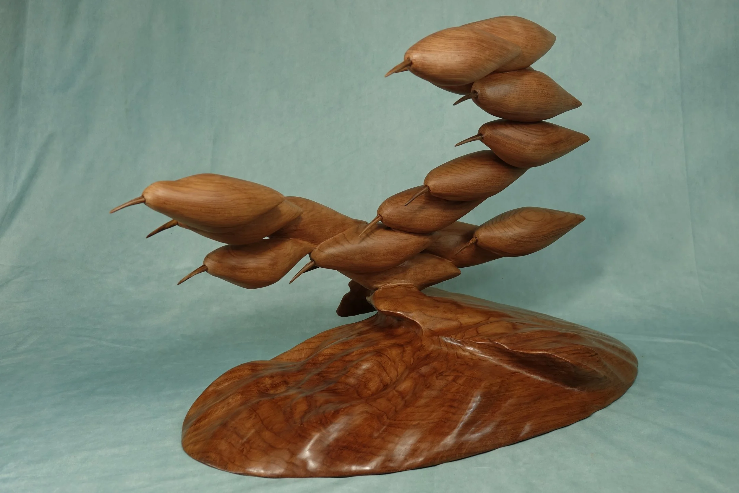 A wooden sculpture resembling a group of birds perched on a branch.