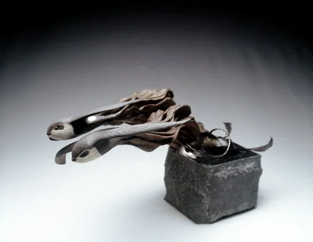 Sunglasses with paper or cloth attached hanging over a small black stone or brick.