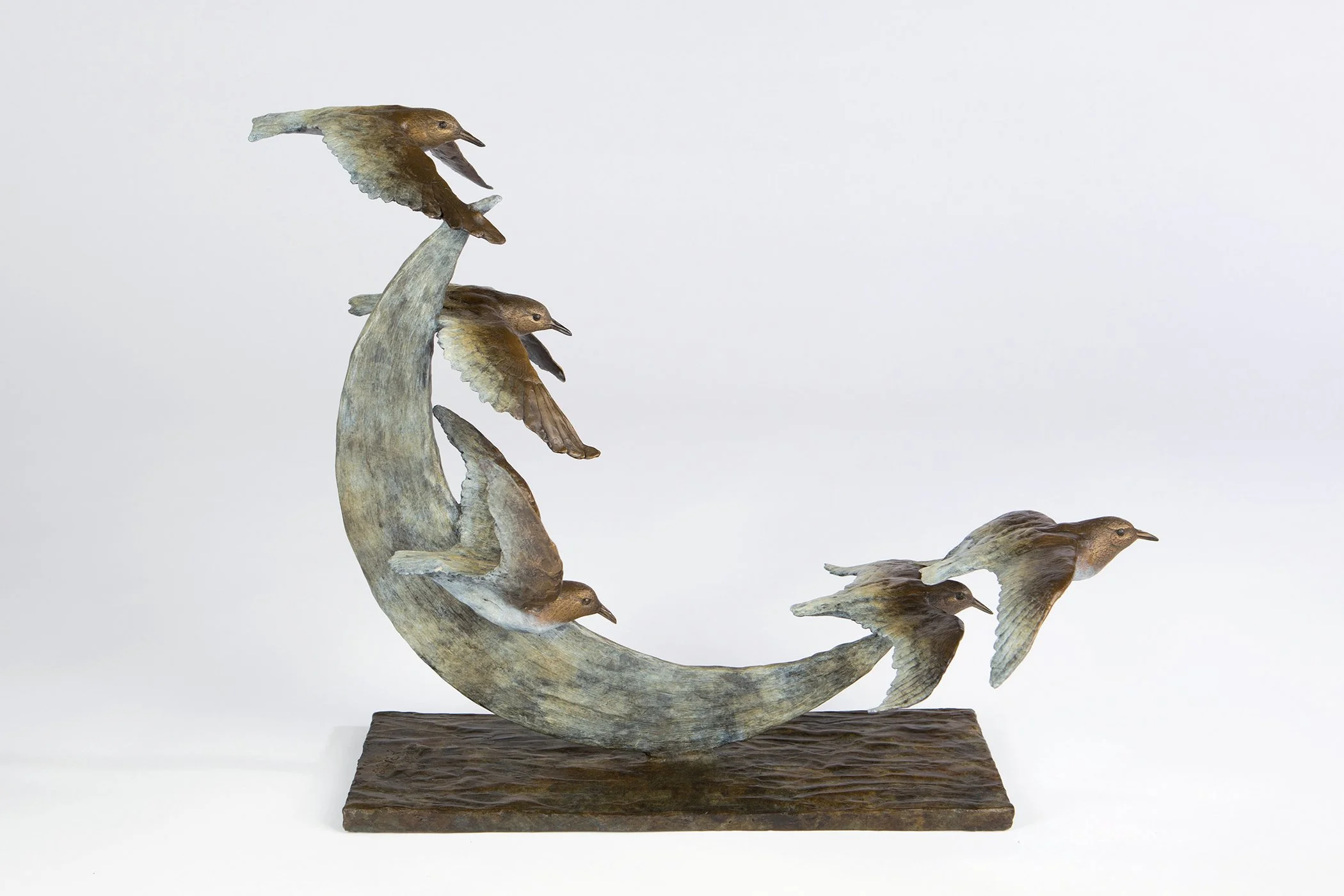 Wooden sculpture of birds perched on a curved branch with a base.