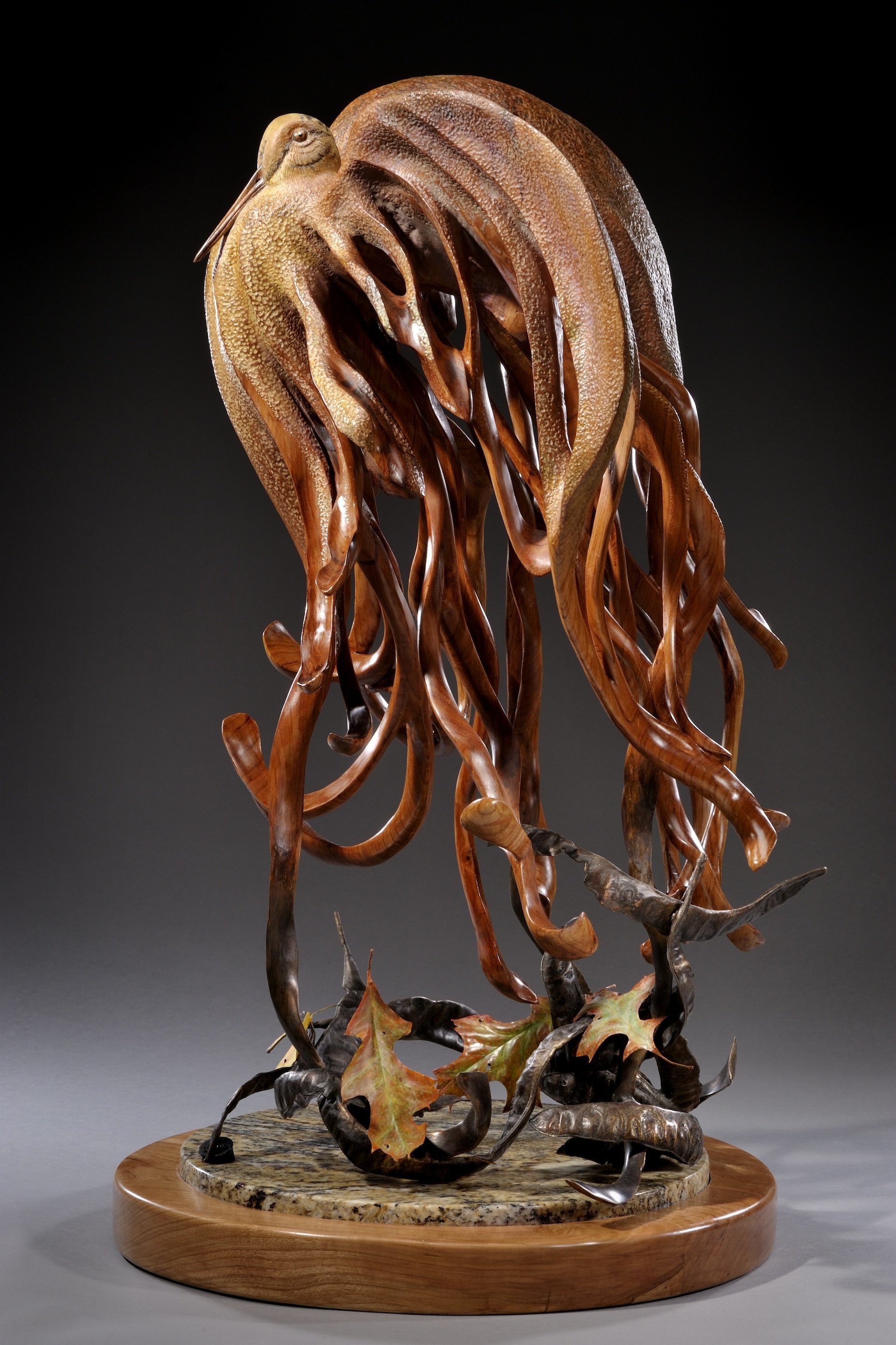 A sculpture of a bird with a brown body perched on a base made of intertwined leaves and vines, mounted on a wooden platform.