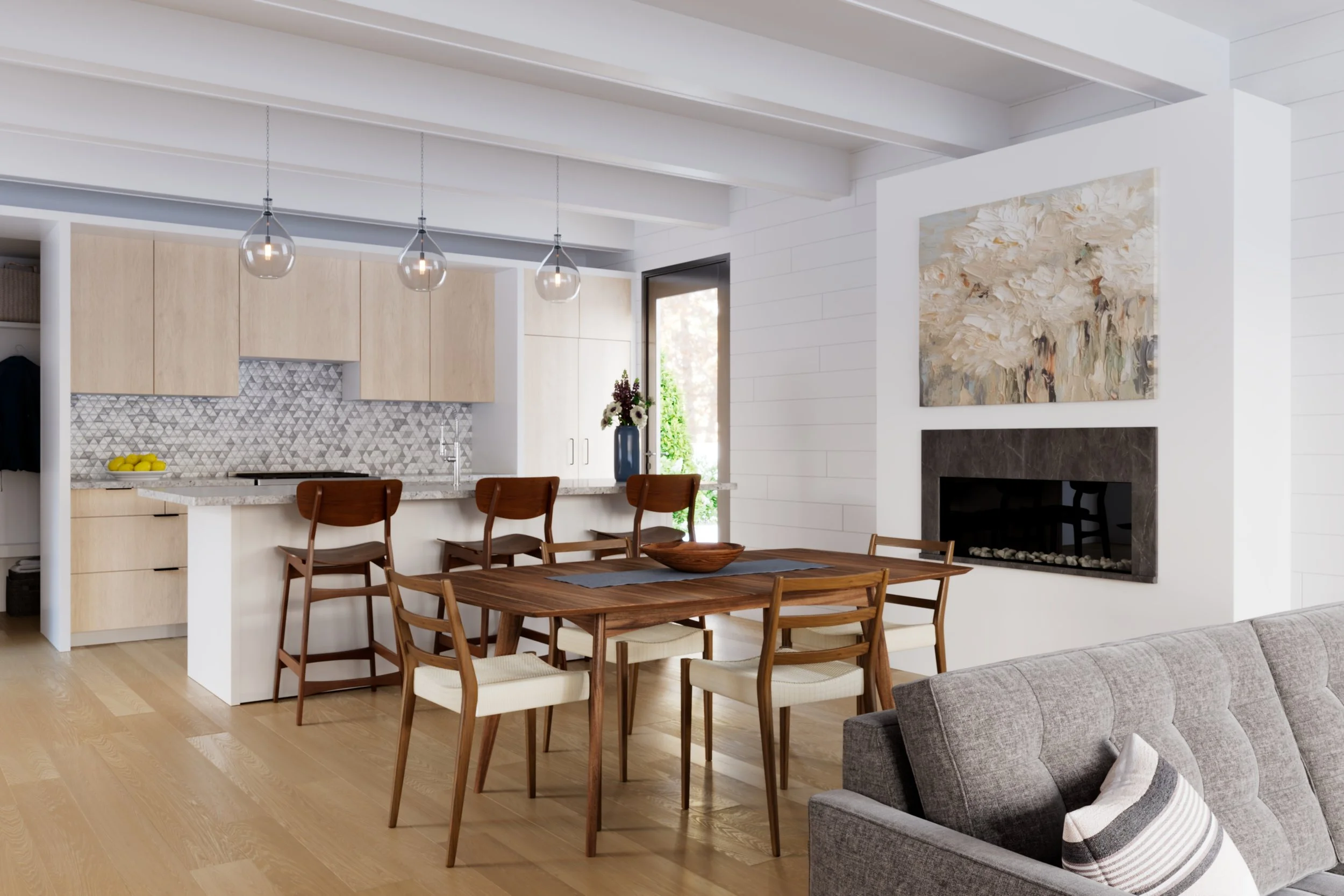 A modern, open-concept living and kitchen area with white walls and ceiling beams, light wood flooring, a dining table with chairs, a gray sofa, a fireplace with a large abstract painting above, and a entry door with a glass side window. Hanging pendant lights illuminate the space.