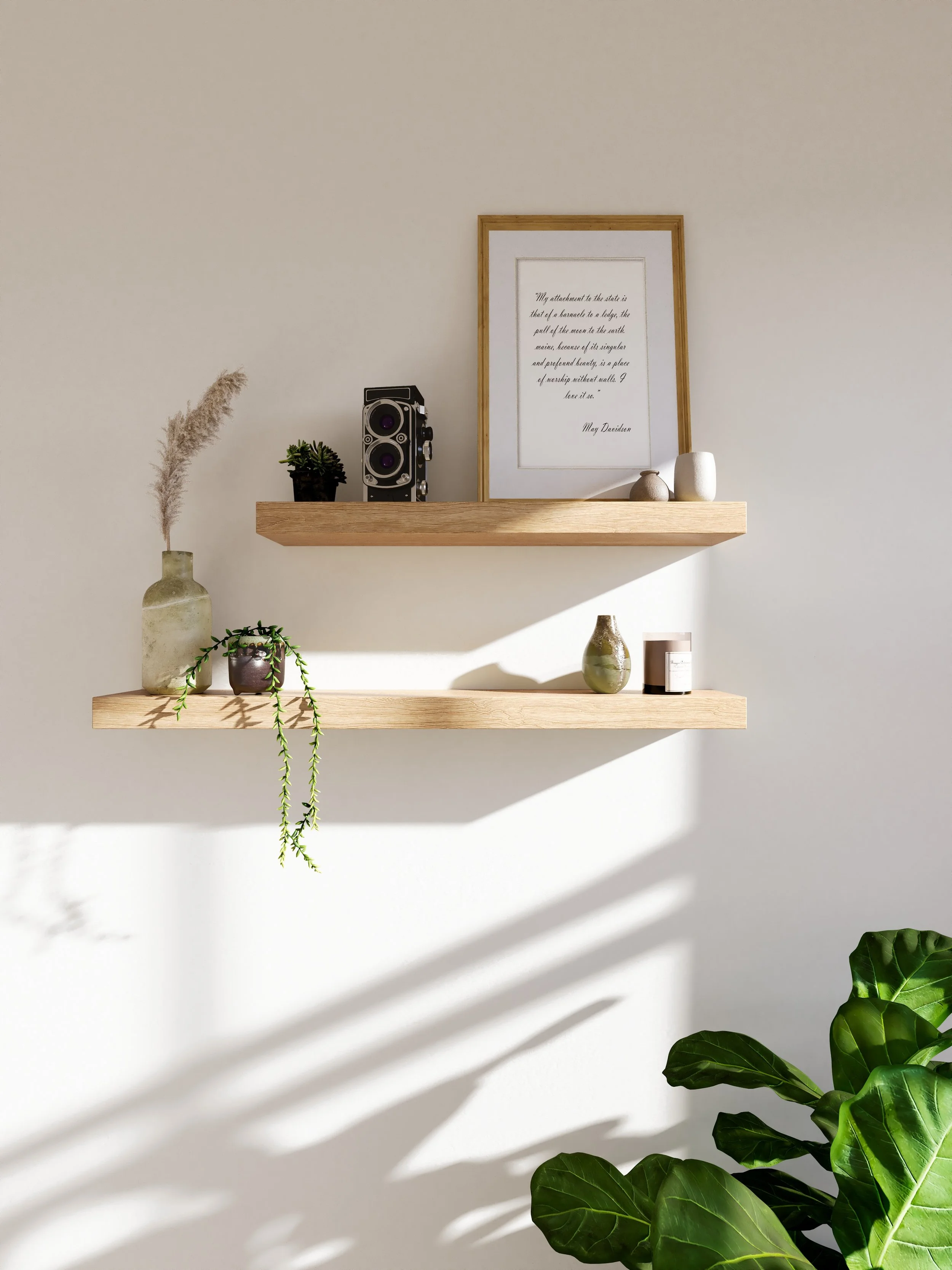 Two wooden floating shelves on a white wall with various decorative items: a small plant and a vintage-style speaker on the top shelf, a vase and a candle on the bottom shelf, and a framed quote by May Davidson on the top shelf. There are shadows cast on the wall.