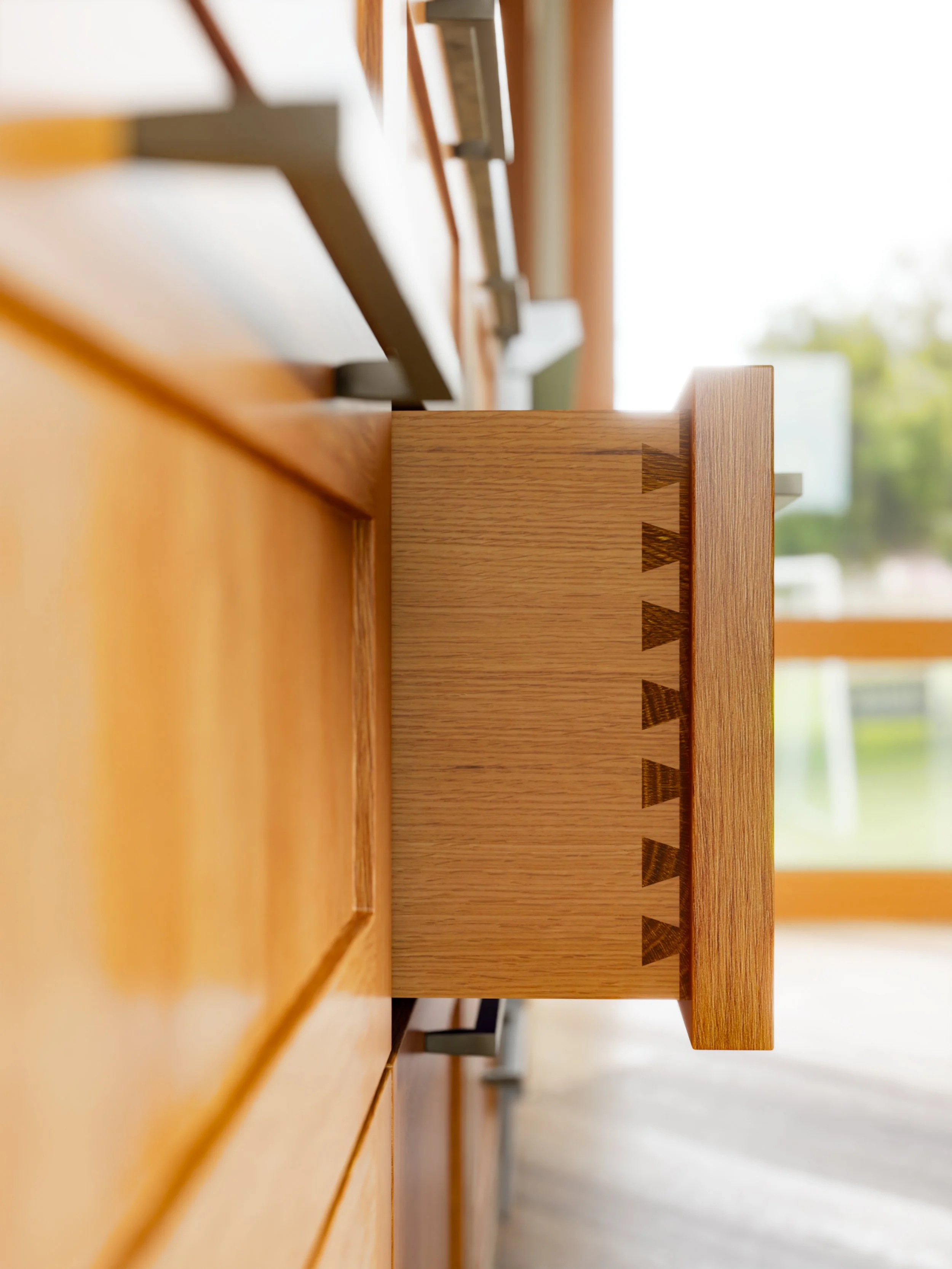 Close-up of a wooden furniture piece with dovetail joints, viewed from the side near a window with a tree outside.