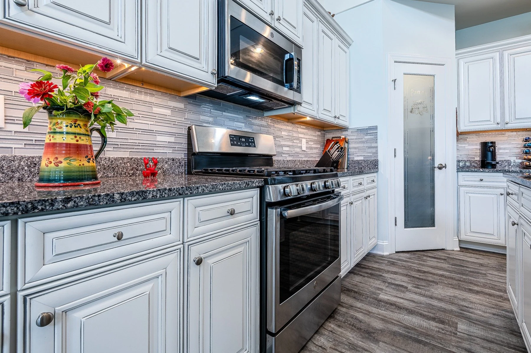 Kitchen range, glass-tile backsplash, and white cabinetry at 28839 W Henry Place.