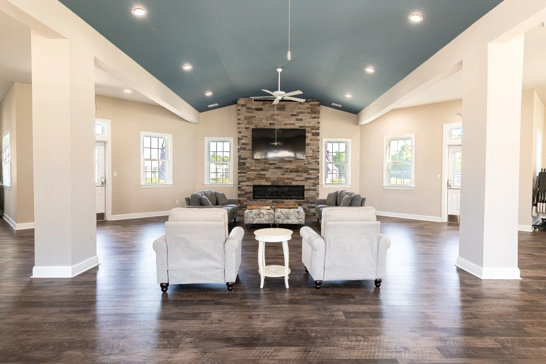 Community clubhouse great room with vaulted ceiling and stone fireplace.