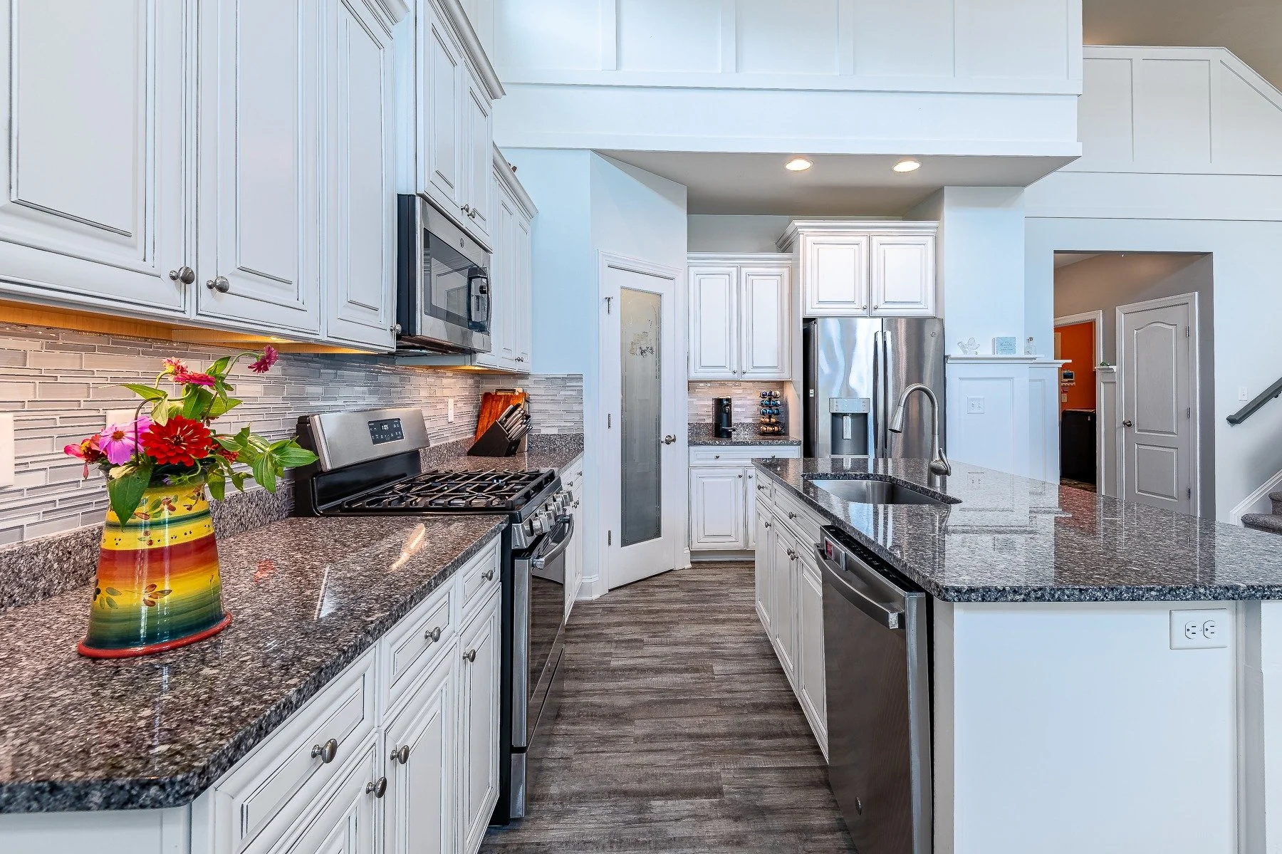 Kitchen with white cabinetry, granite counters, stainless appliances, and island at 28839 W Henry Place.