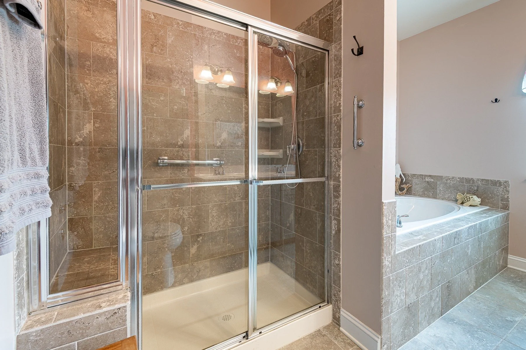 Tiled walk-in shower and soaking tub in the primary bathroom at 28839 W Henry Place.