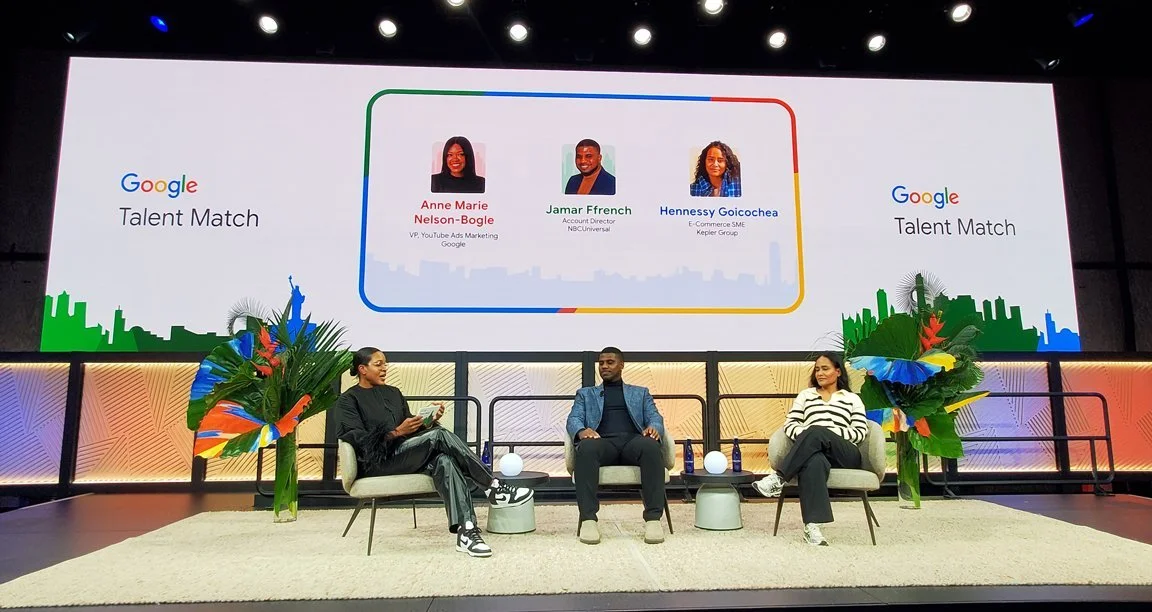 Panel discussion at Google Talent Match event with three speakers on stage, large screen behind displaying names and titles of Anne Marie Nelson-Bogle, Jamar Ffrench, and Hennessy Goicoechea, and decorative plants on sides.