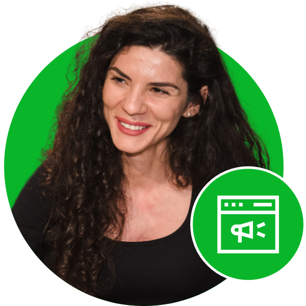 A woman with long, curly dark hair and a bright smile wearing a black top, set against a green screen background with a website design icon in the lower right corner.