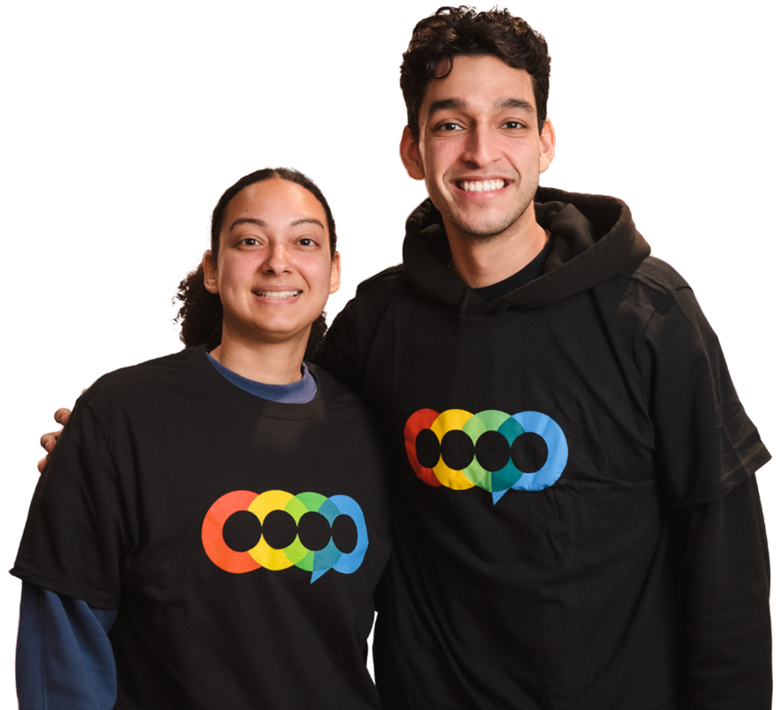 Two young adults smiling, wearing black T-shirts with a rainbow-colored LGBTQ+ pride logo.