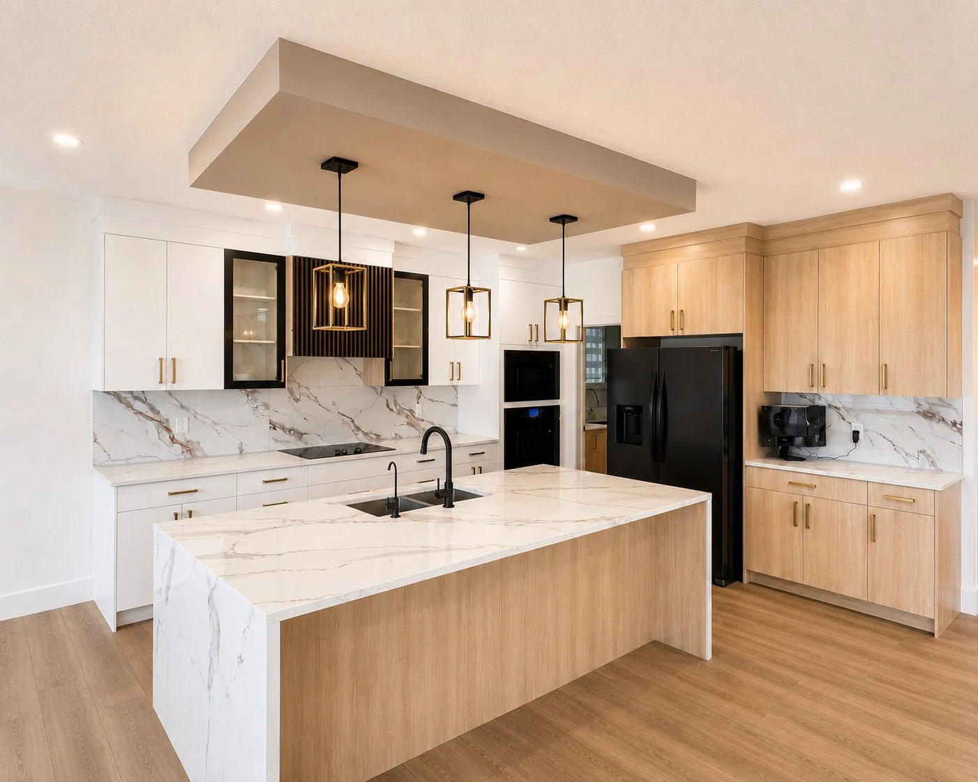 Modern kitchen with white and wooden cabinets, marble countertops, black refrigerator, and hanging pendant lights.