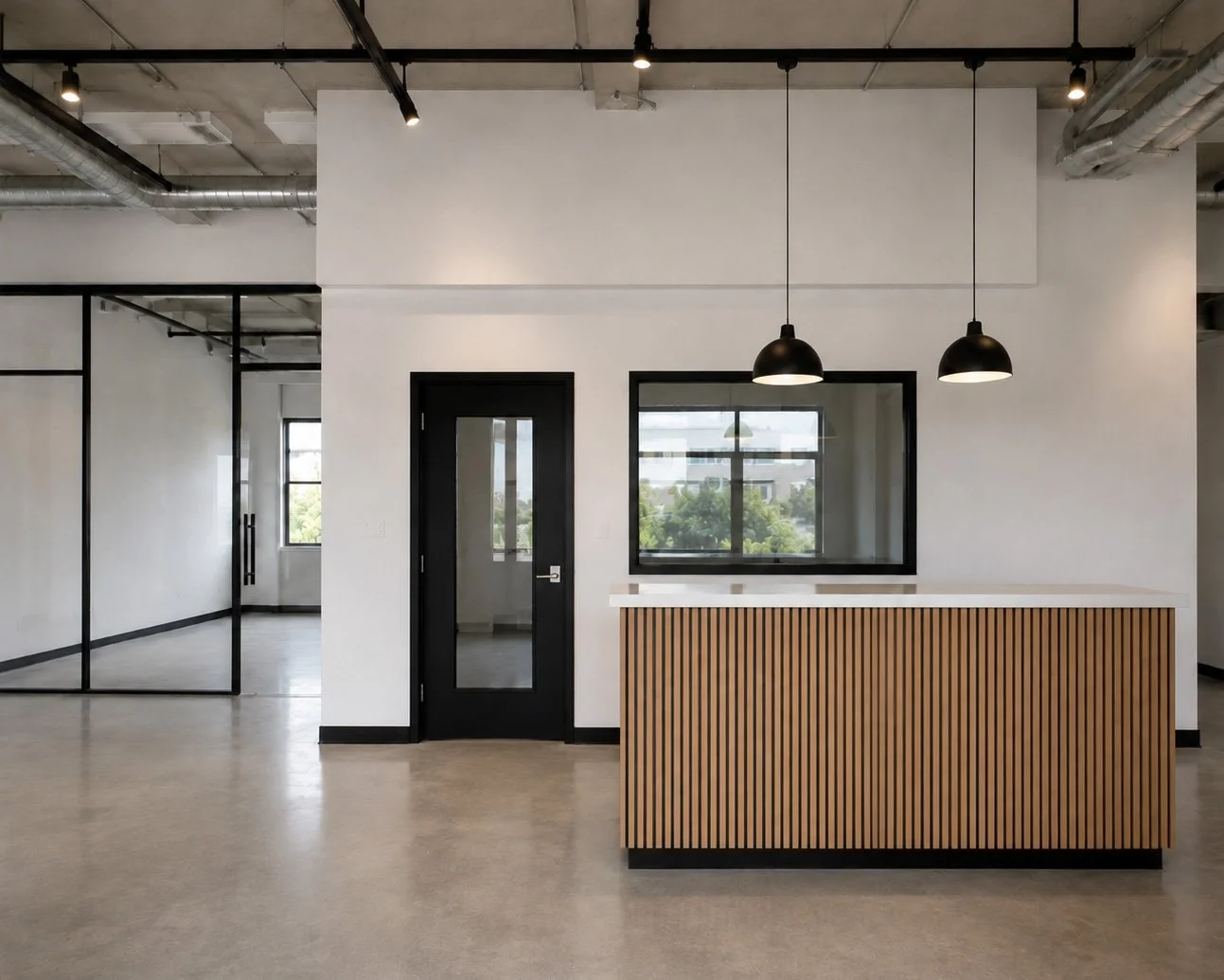 Empty modern office reception area with a wooden slat front desk, black door, window, and black pendant lights, exposed ceiling pipes, and glass wall partitions.