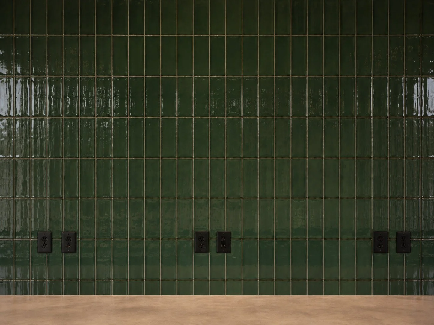 Green tile wall with electrical outlets at the bottom and a wooden surface in the foreground.