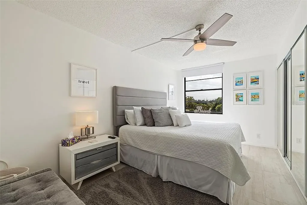 A bedroom with a bed, nightstand, and window with a view of trees outside.  For a luxury accomodation