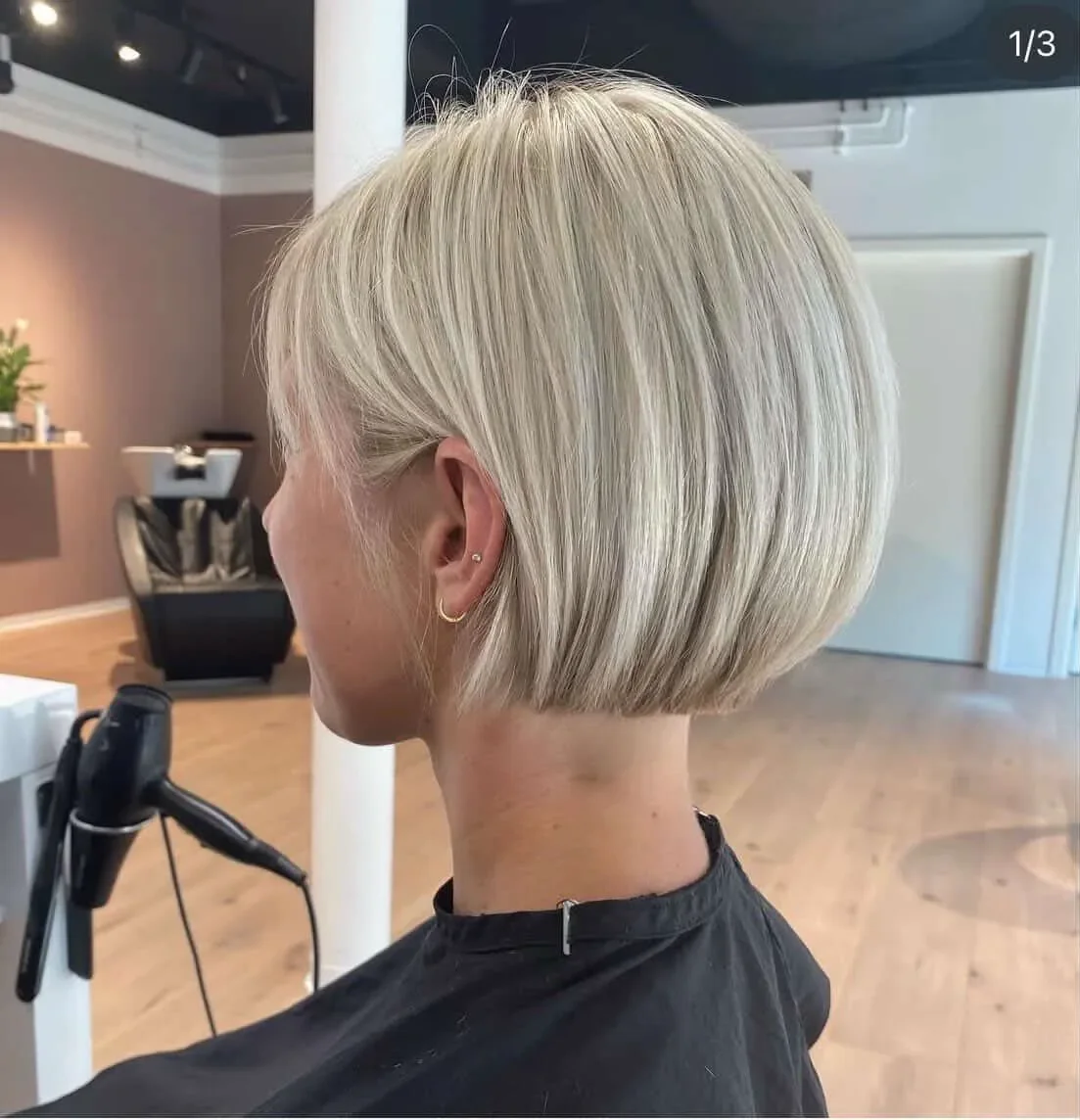 En person med blond, kort frisure, set fra siden i en frisørsalon.