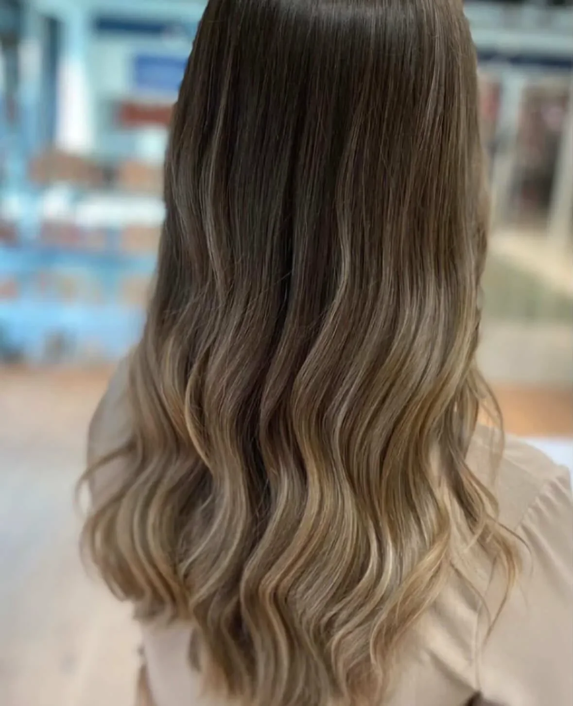 Billedet viser en kvindes hår set bagfra med brunt til blond ombré og vævede krøller.