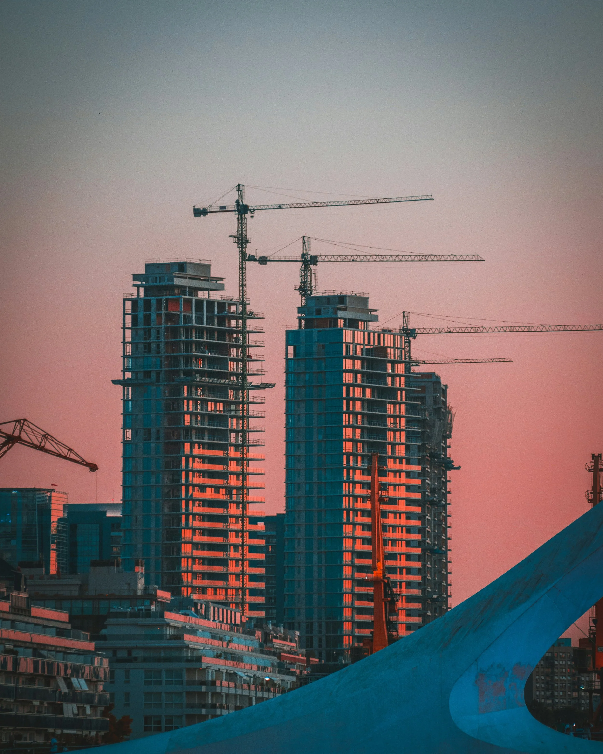 High-rise buildings under construction against a dusk sky.