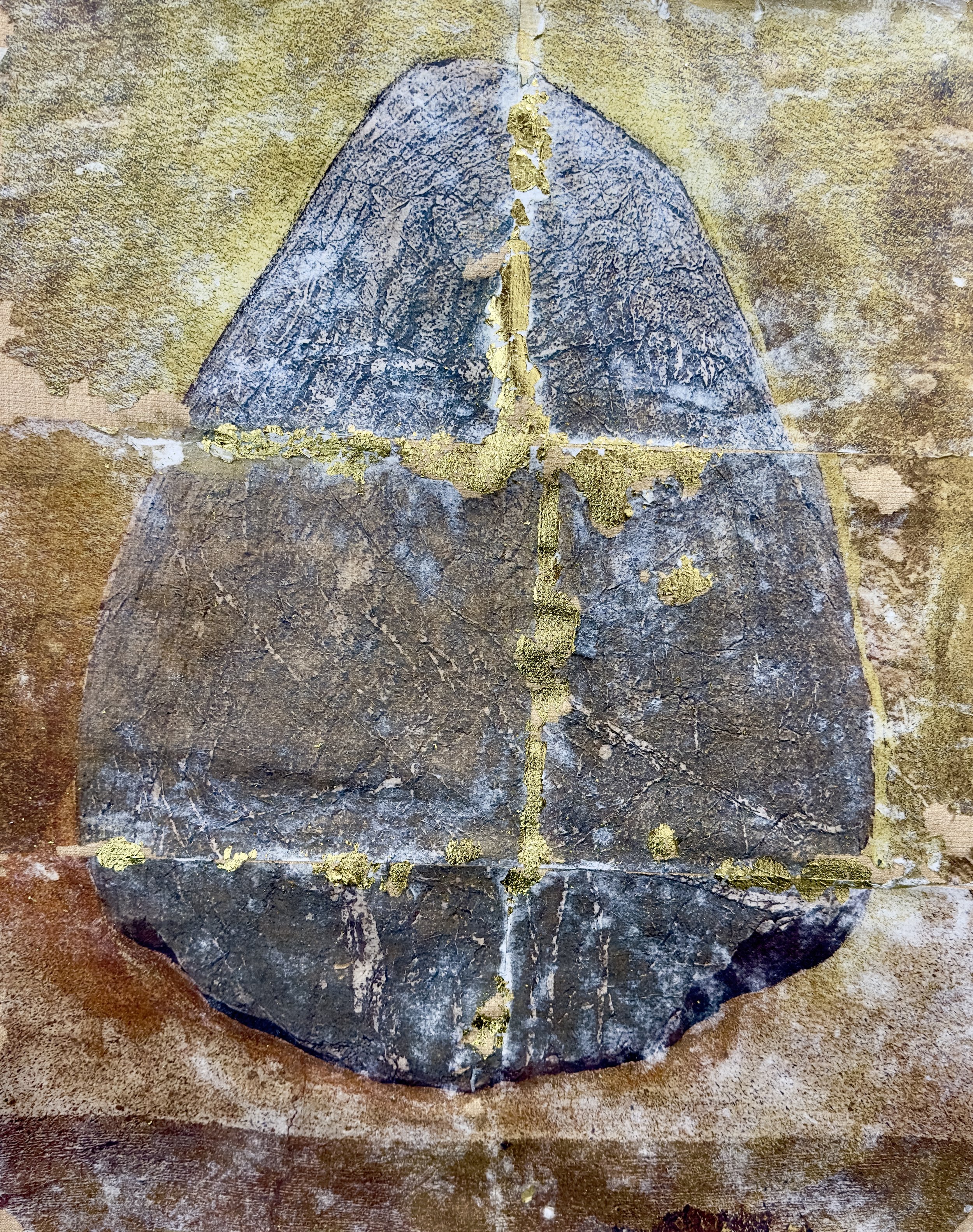 A cracked and weathered black stone with gold leaf accents, possibly a religious or ceremonial artifact, resting on a rough brown surface.