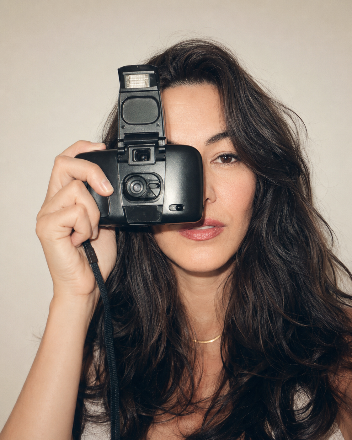 Angelina, founder and creative director of Edit House, holding a vintage instant camera to her eye
