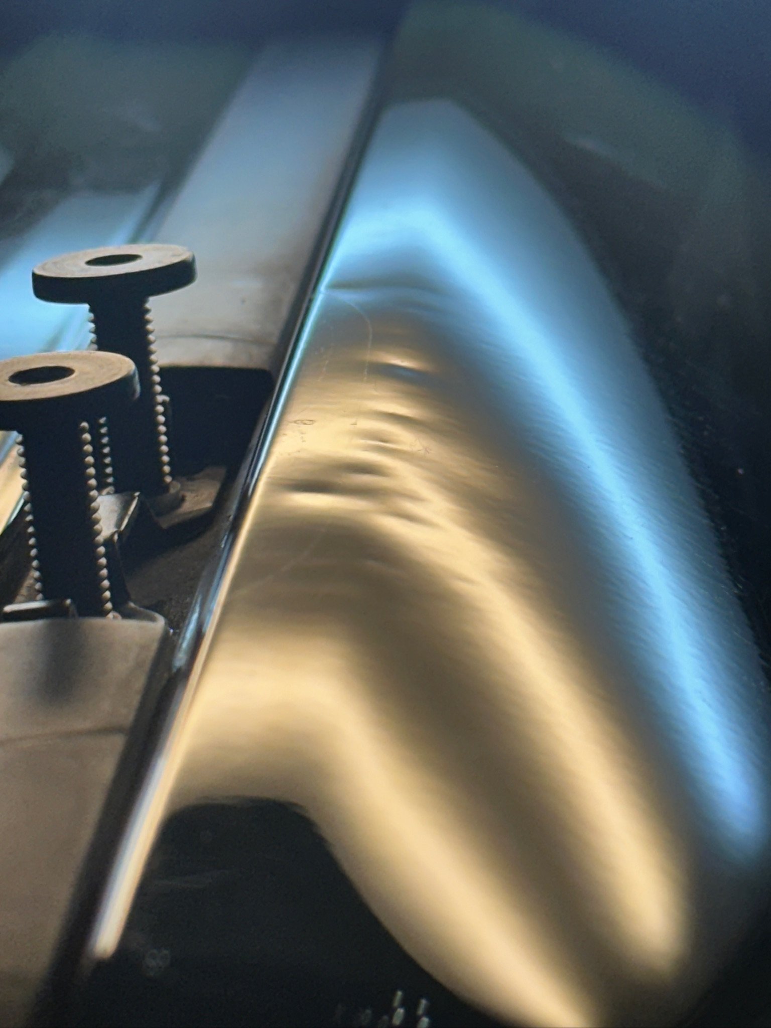Close-up of a gas stove with two black burners and a silver metallic surface, with a focus on the burners and the reflective surface of the stove.