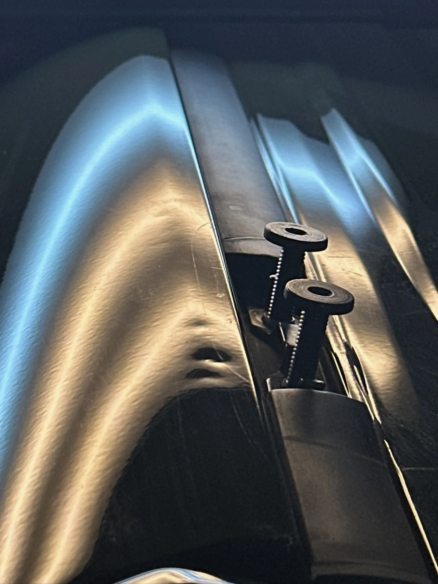 Close-up of a shiny stainless steel commercial kitchen sink with a black drain stopper and chain.