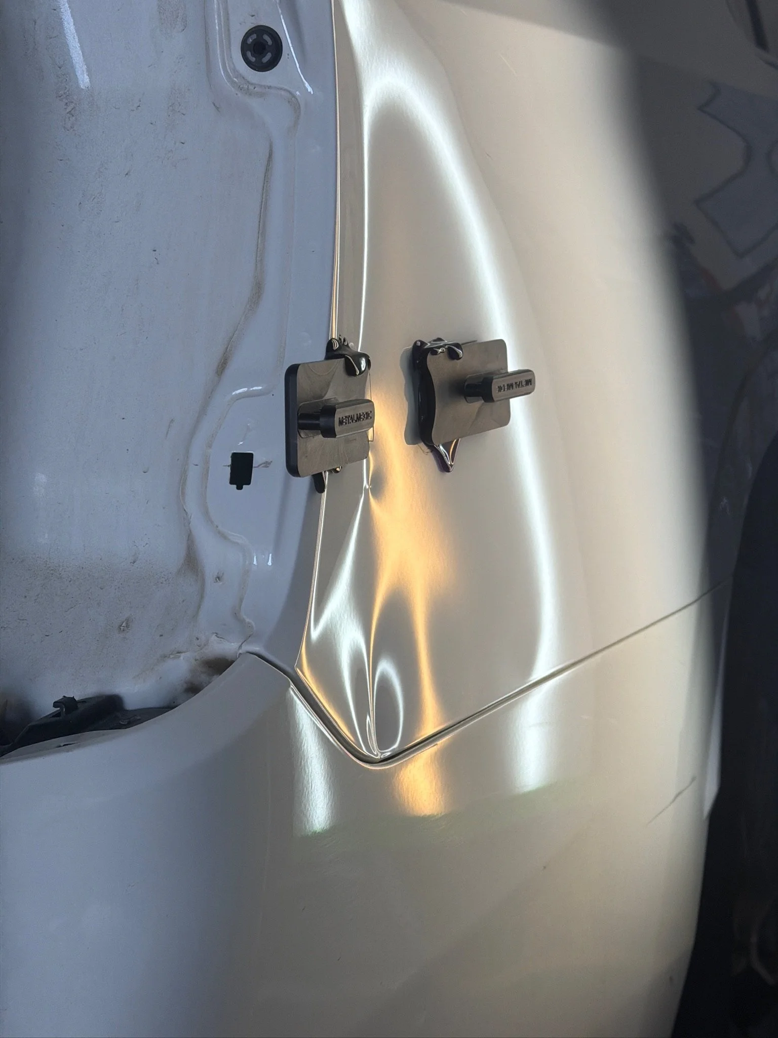 Close-up of a metallic stainless steel surface with two electrical component pads labeled 'RESISTANT' and 'METAL M.