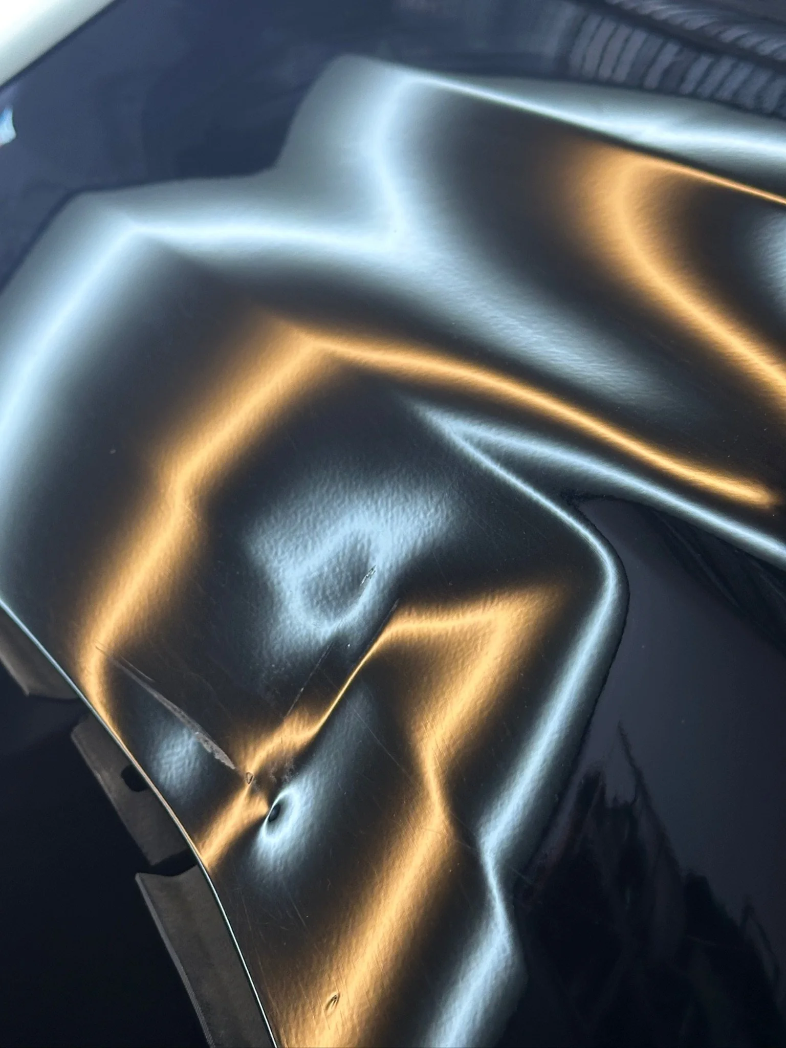 Close-up of a crumpled silver or metallic foil or sheet, with reflections of light creating bright and dark areas.