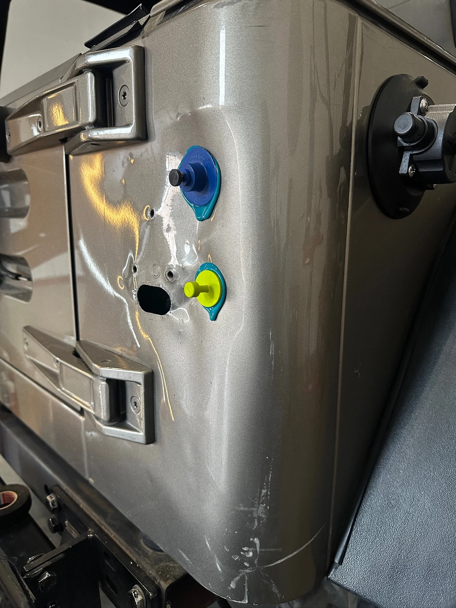 Close-up of a stainless steel appliance, possibly a toaster oven or microwave, with a blue and green suction cup attached to its surface.