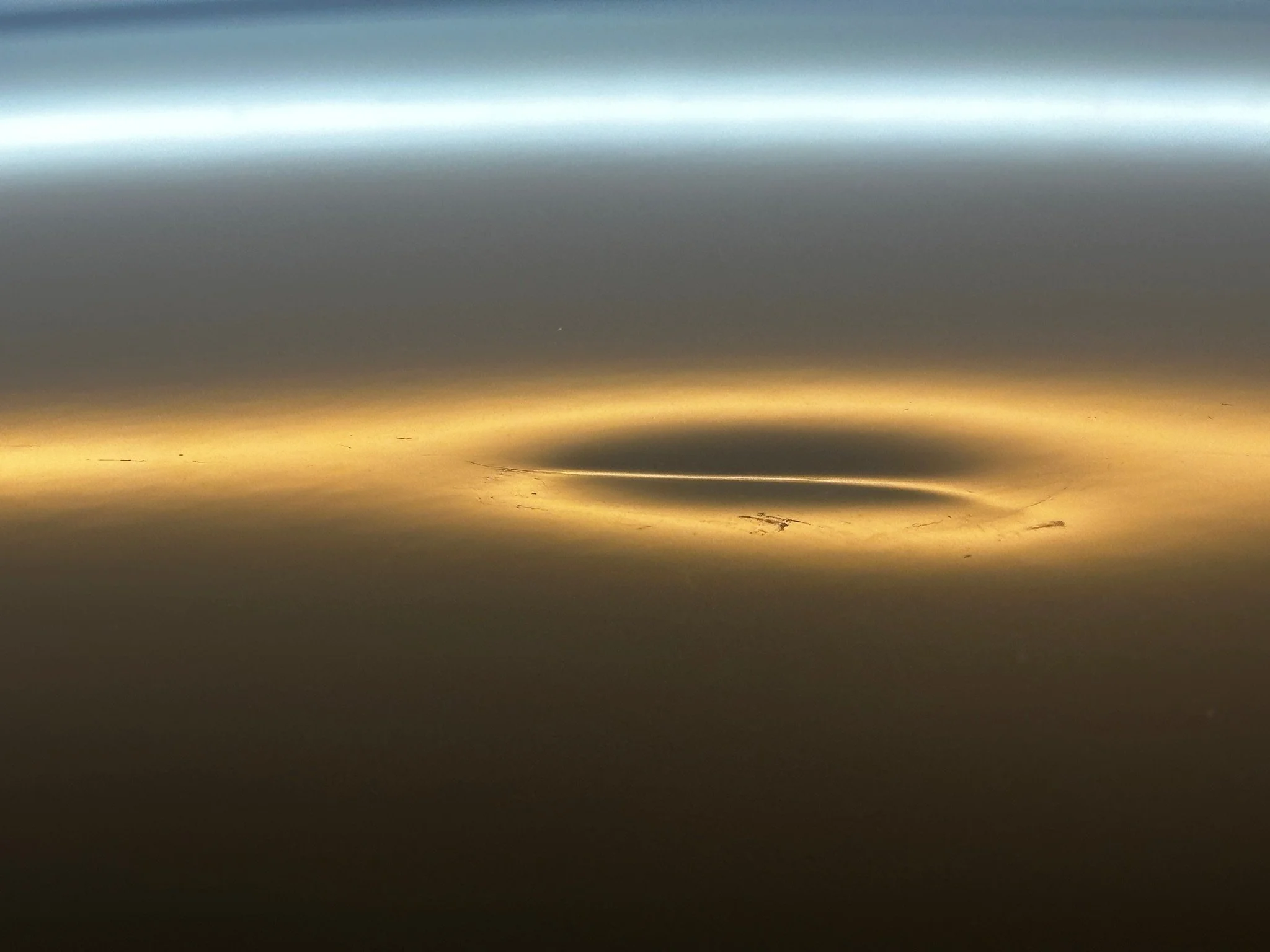 A metallic surface with gradient colors shifting from silver at the top to gold at the bottom, with slight scratches and reflections.