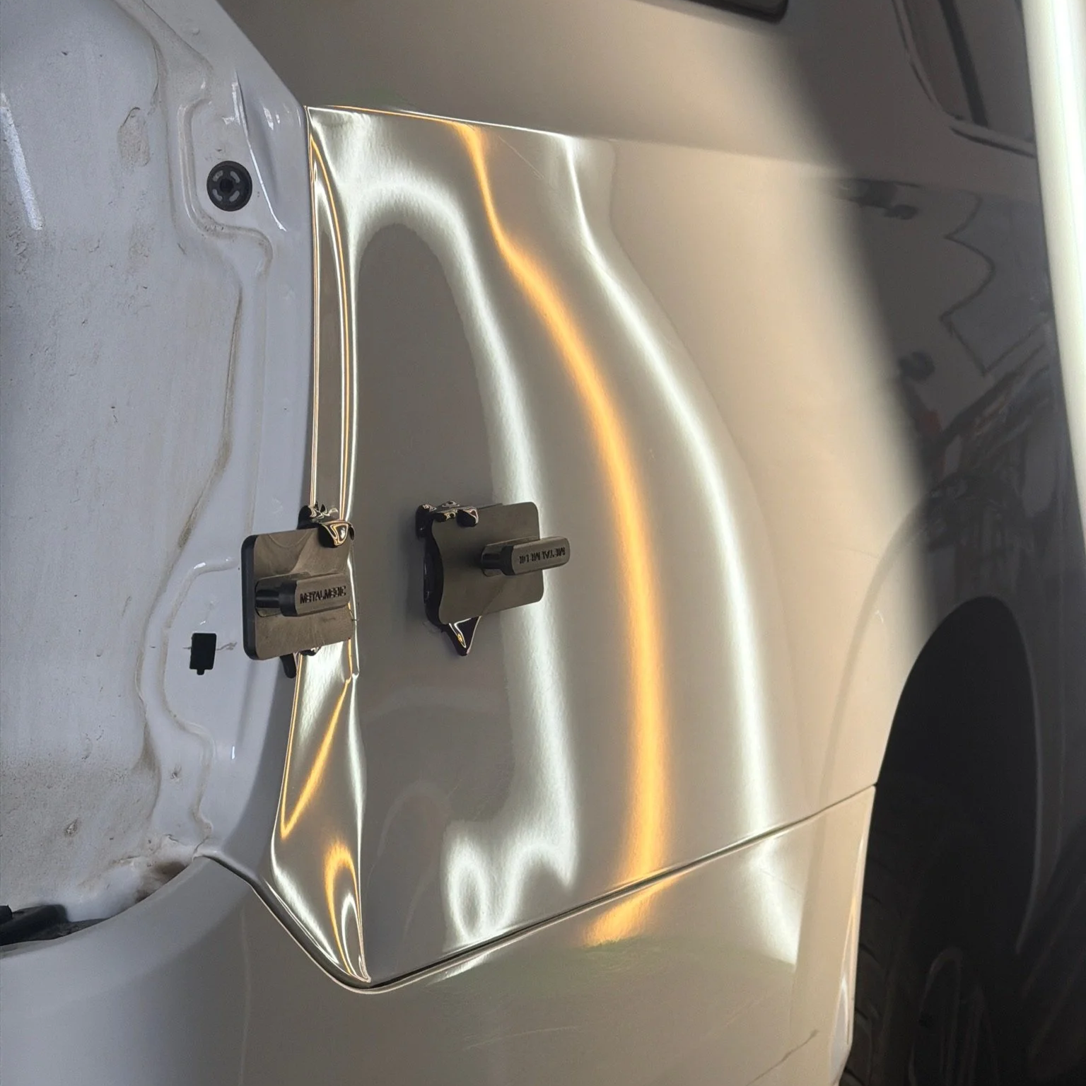 Large fender dent under PDR reflection lighting before paintless dent repair in Arvada Colorado