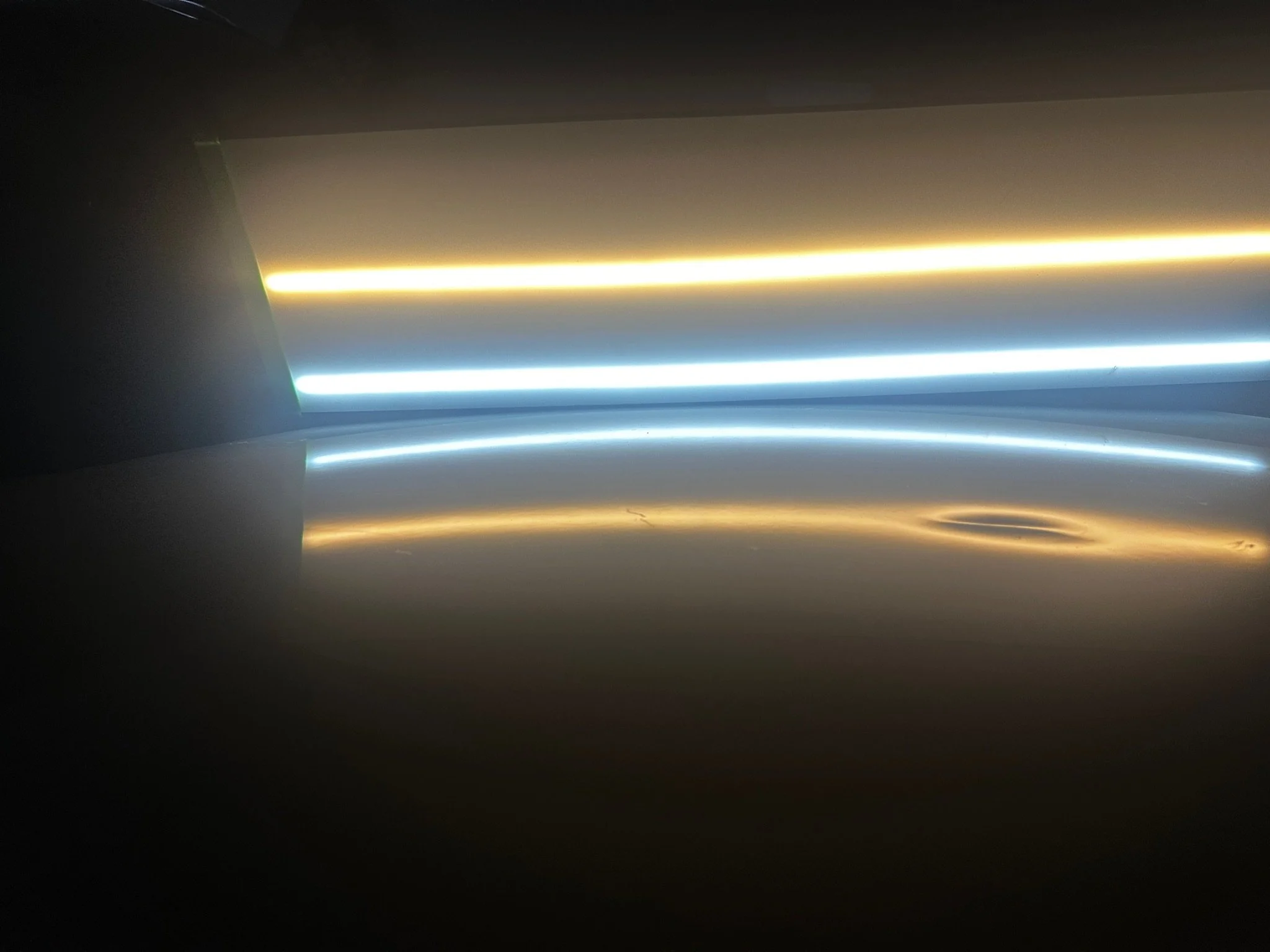 Close-up of several illuminated LED light strips with glowing white, yellow, and blue lights.