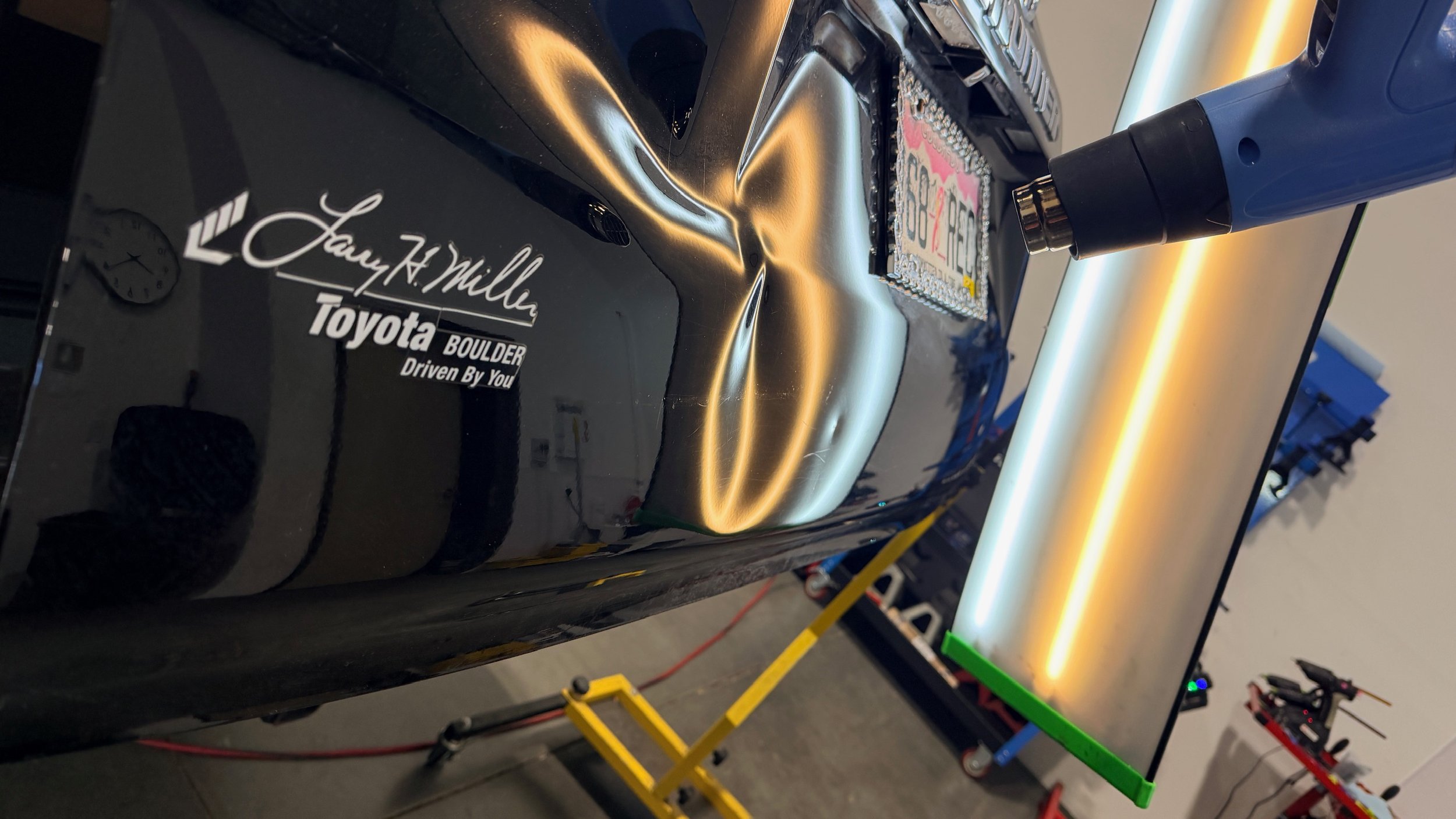 Rear impact dent highlighted under paintless dent repair reflection lighting