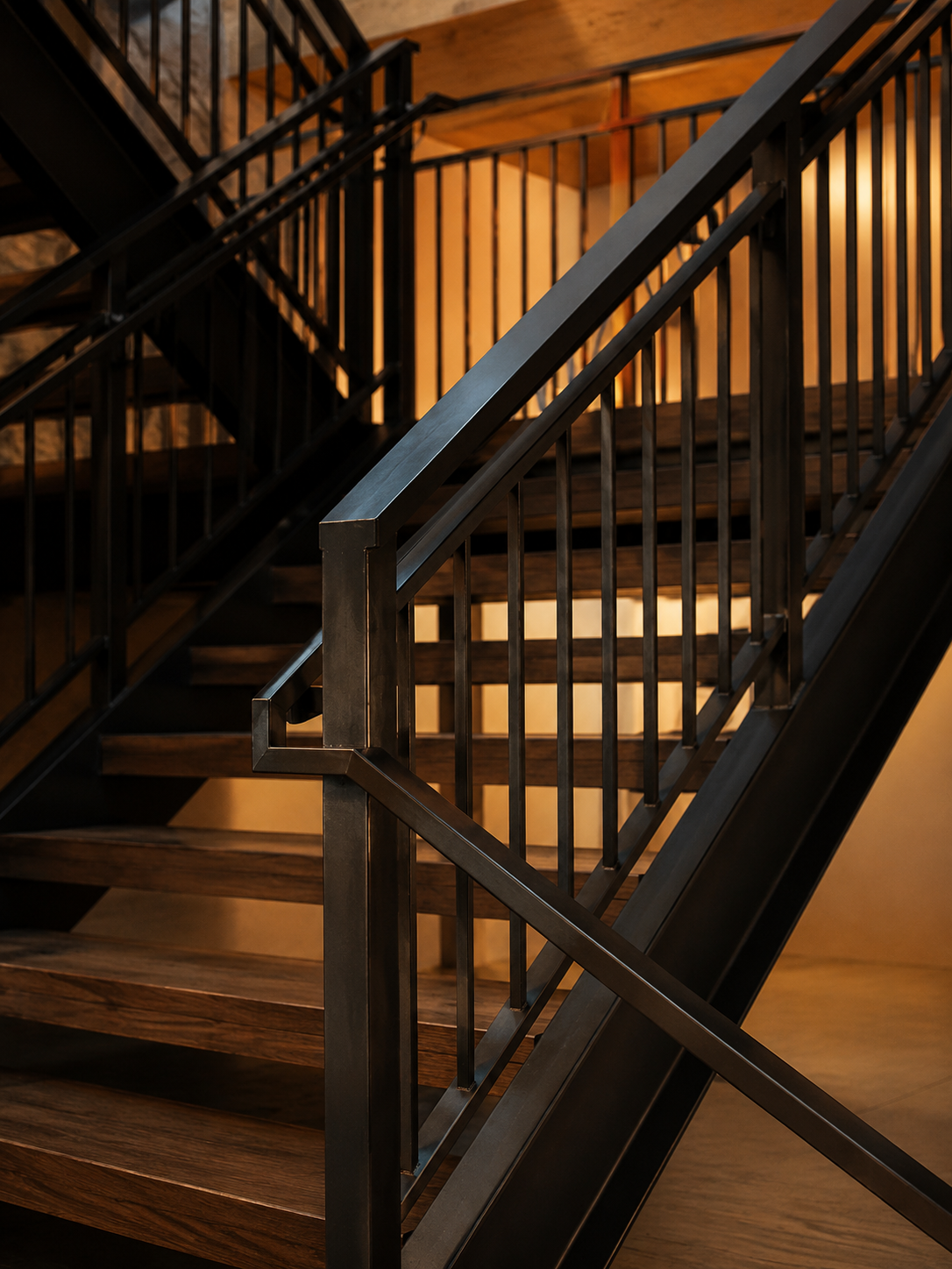 Close-up of a modern staircase with black metal railings and wooden steps leading to an upper level.