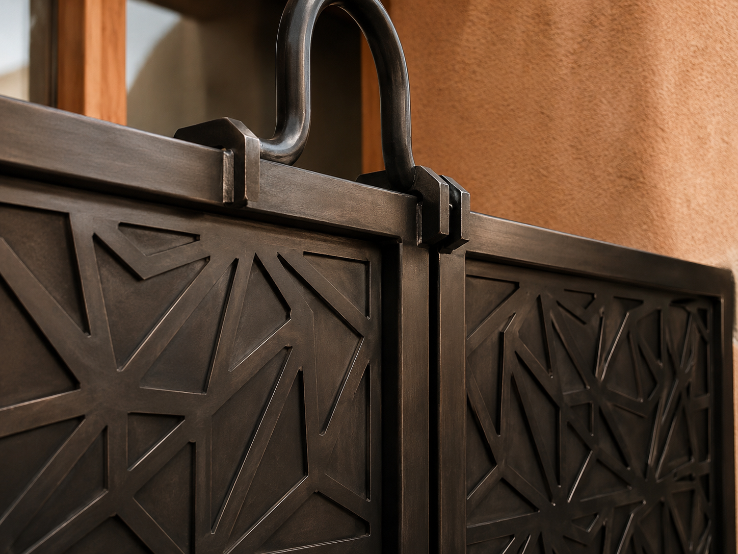 Close-up of a decorative black metal folding screen or room divider with geometric cutout patterns, and a handle on the top. Part of a wooden frame is visible. Backgrounds include a tan wall and another wooden structure.