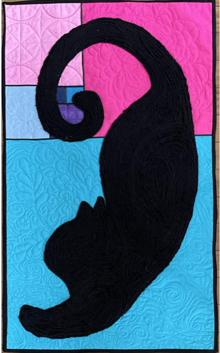 A quilt with a black cat silhouette on a patchwork background of pink, purple, and blue fabrics.