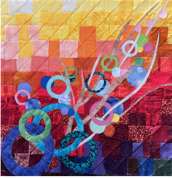 Colorful quilt with circular fabric appliqués and abstract branch design.