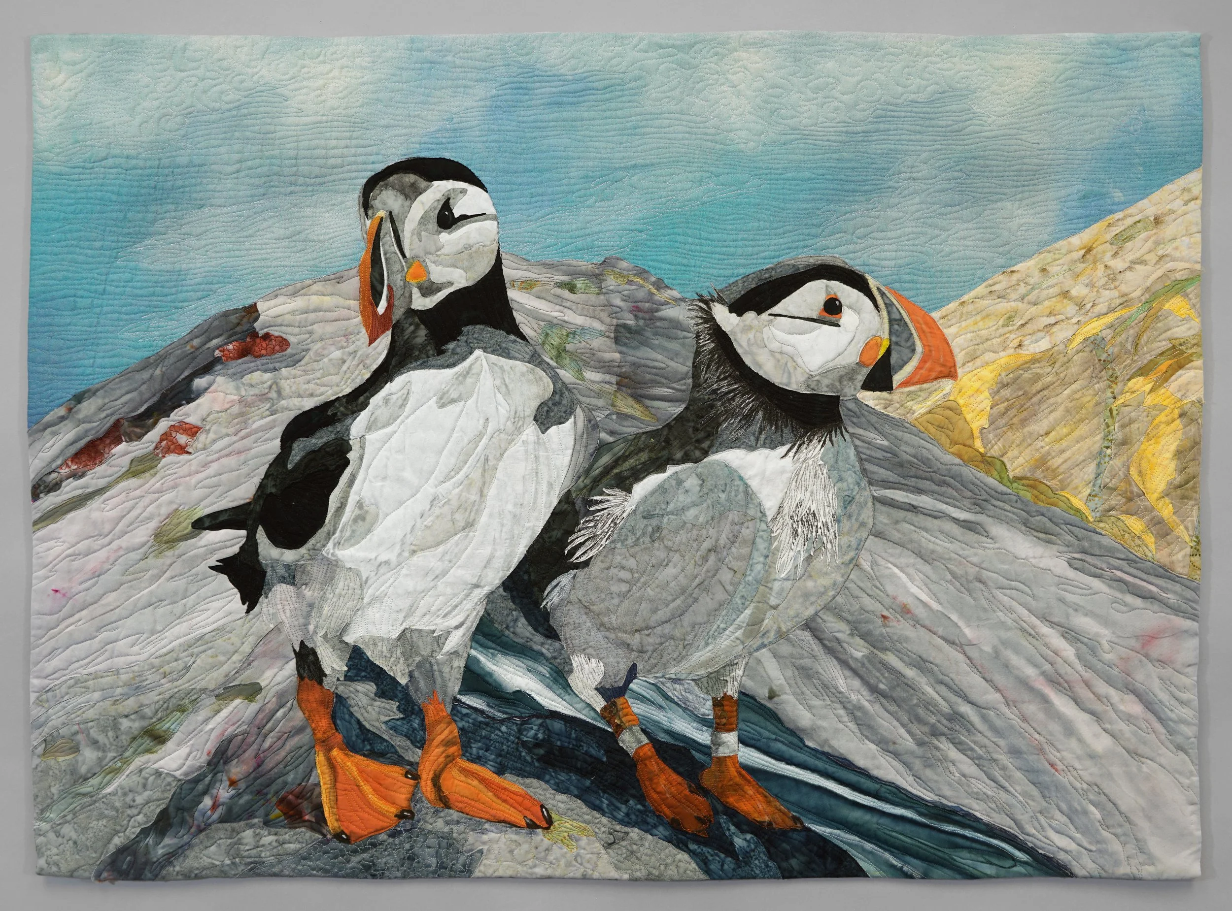 Puffin Pals: Puffin Pals, a fiber art quilt by Janet Fox depicting two puffins standing on rocky terrain.
