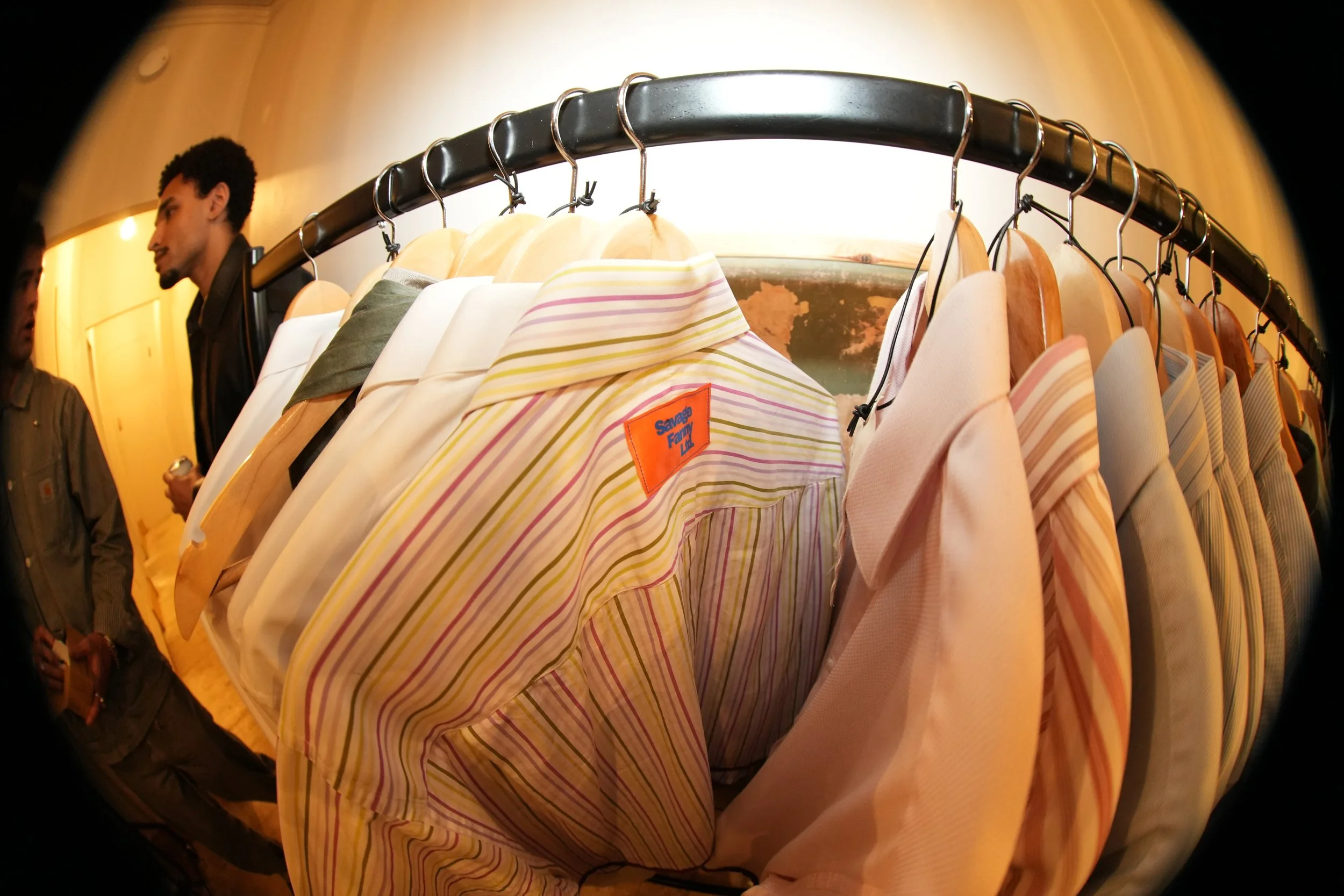 A clothing rack with various shirts and jackets hanging on hangers.