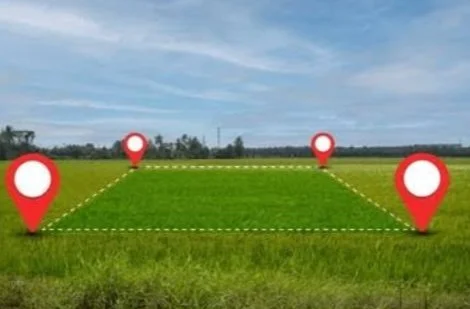 Open grassy field with four large red map markers, two on each side, surrounding a rectangular area marked by dashed lines.