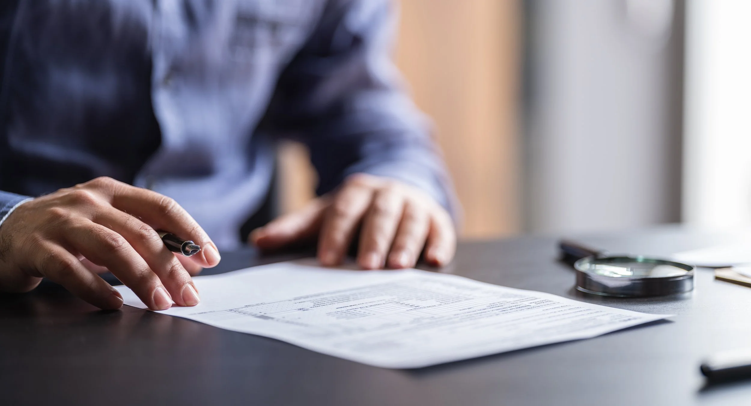 Close-up of a person reviewing financial documents with a pen during the tax planning process.