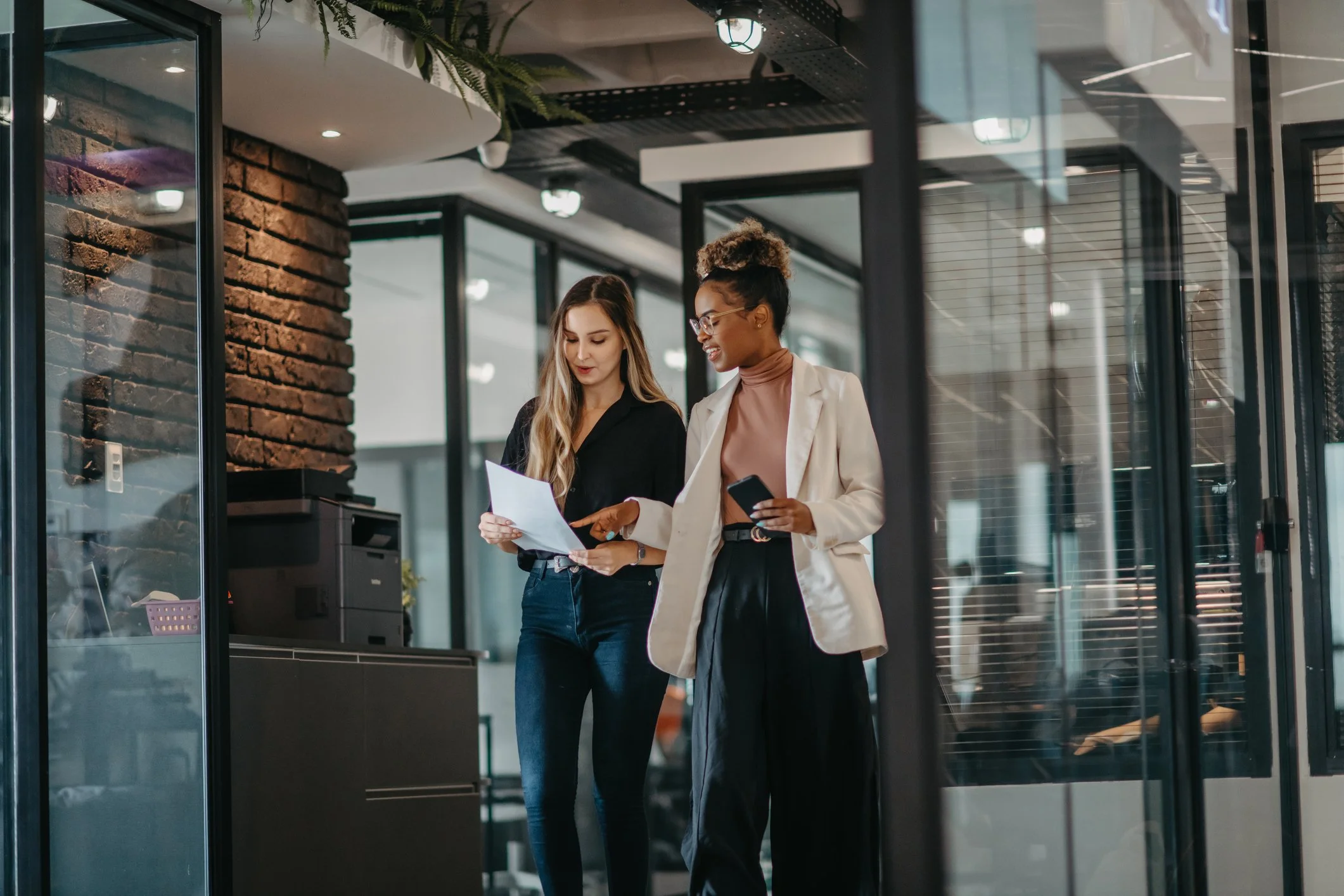 Two business professionals reviewing documents together in a modern office.