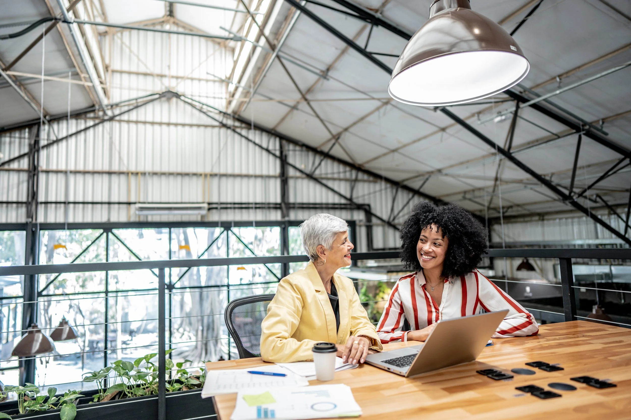 Two business professionals discussing financial documents at a table with a laptop.