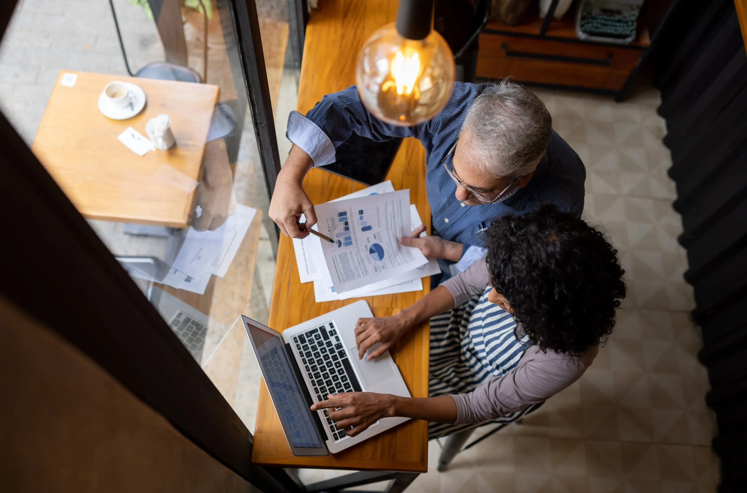 Two business professionals reviewing financial charts and reports together at a desk with a laptop.