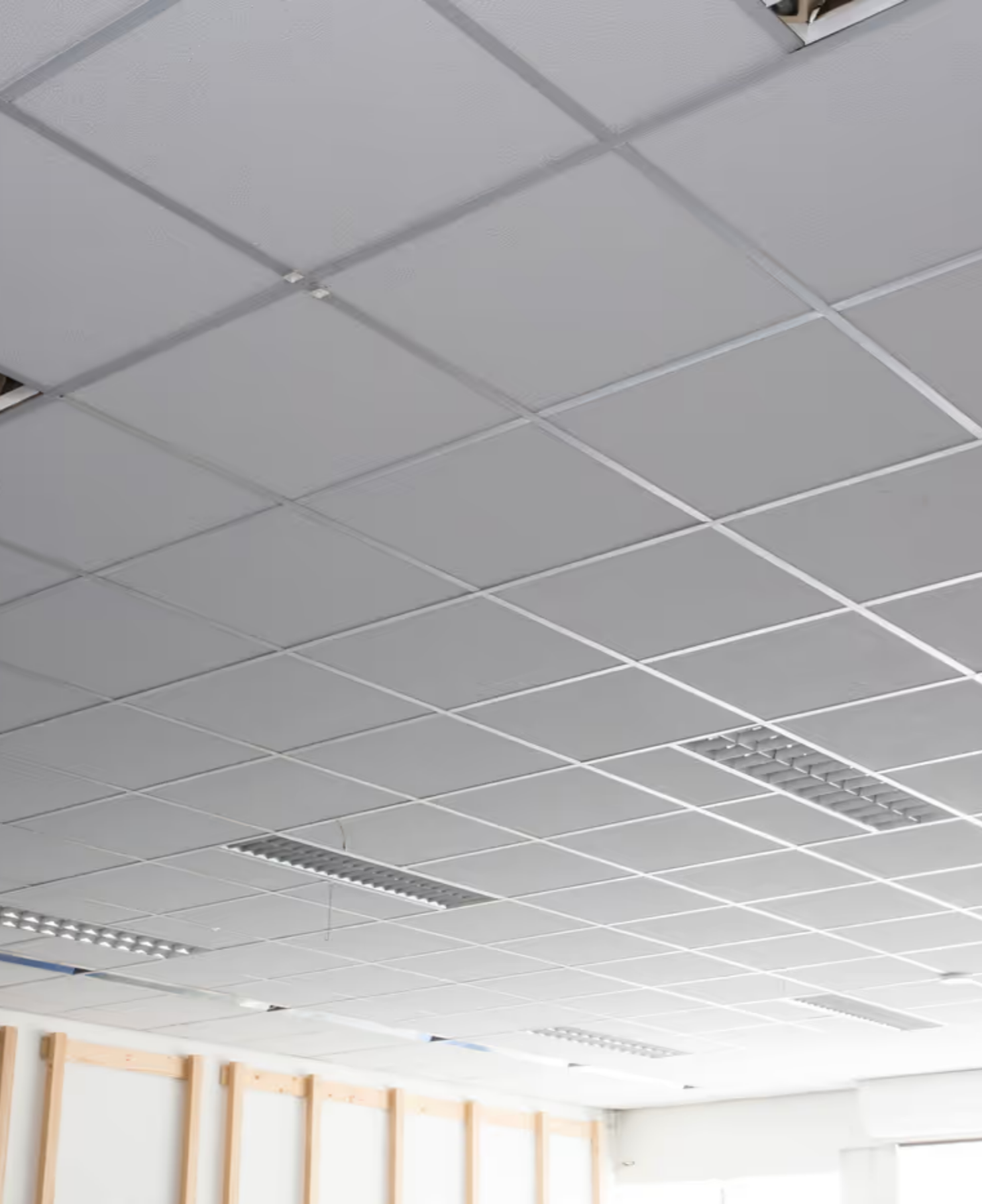 Ceiling tile grid with some ceiling tiles missing in an unfinished room.