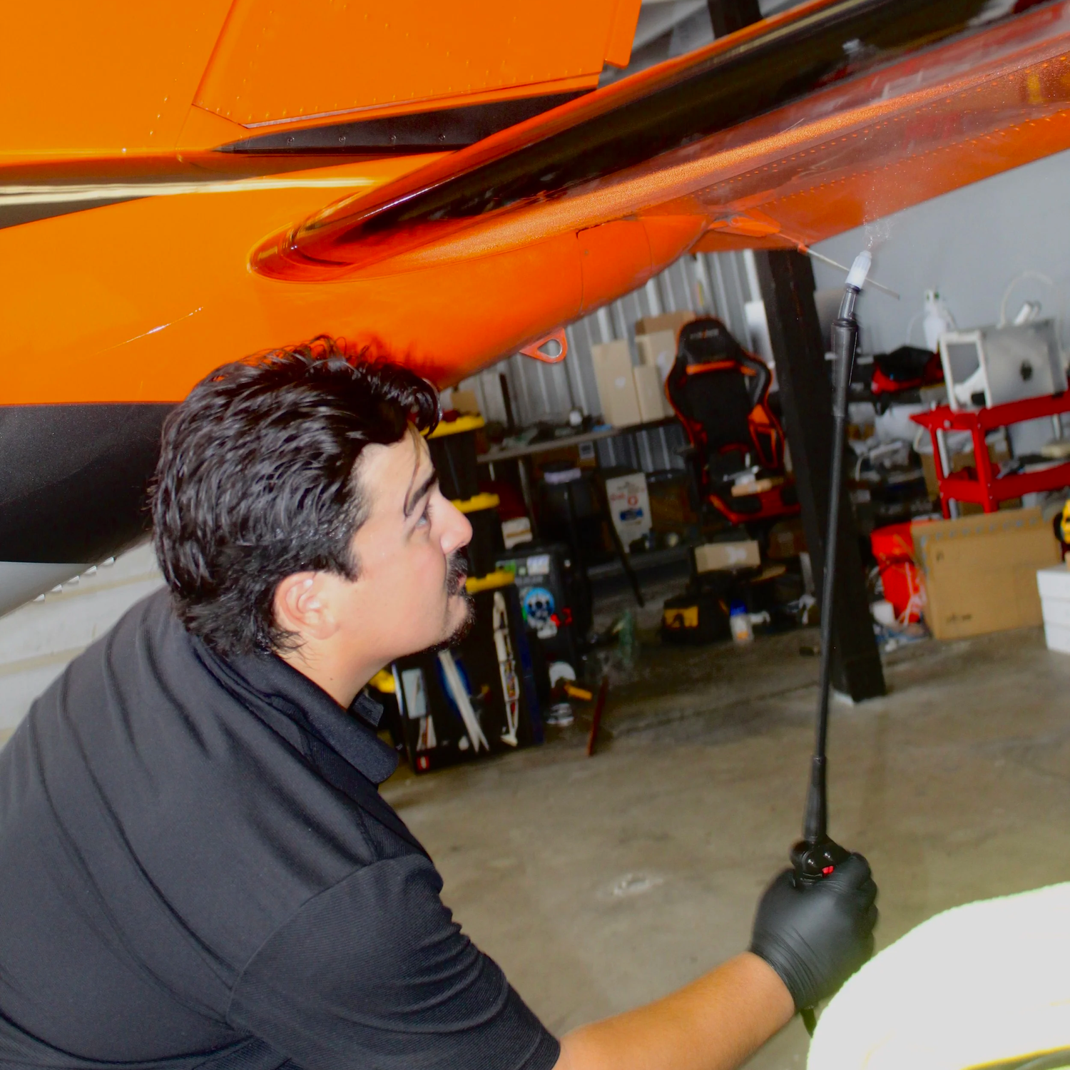 Technician detailing the underside of a Piper PA-46 wing in a hangar