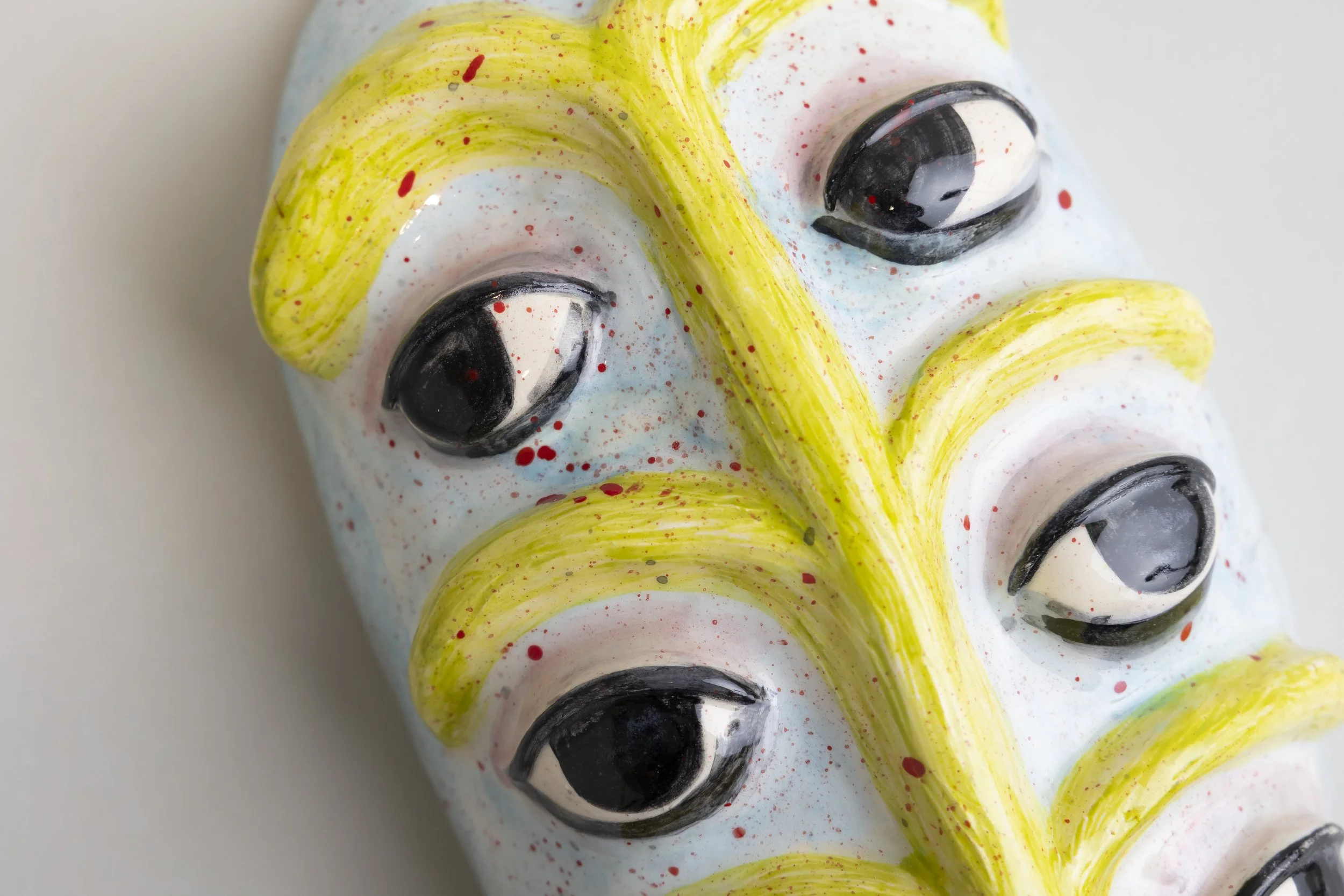 Close-up of a colorful ceramic mask with yellow, black, red, and blue painted details.