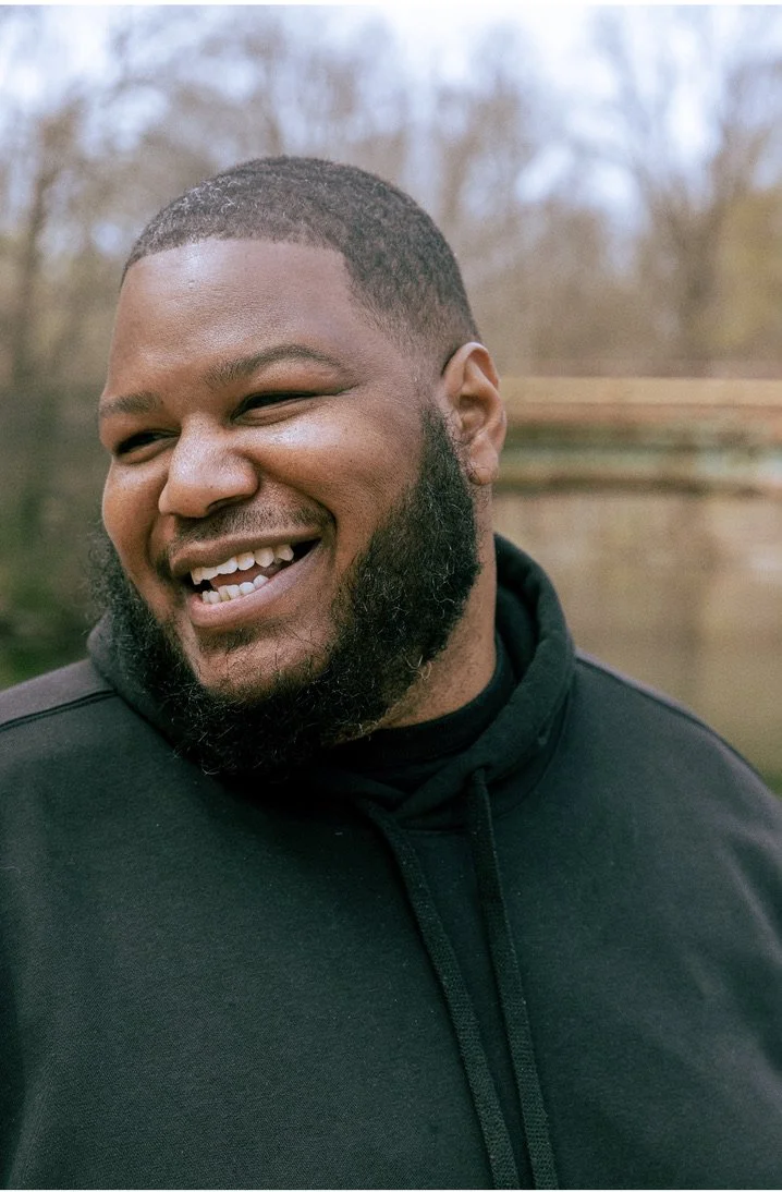 portrait of a young black man with a black hoodie smiling