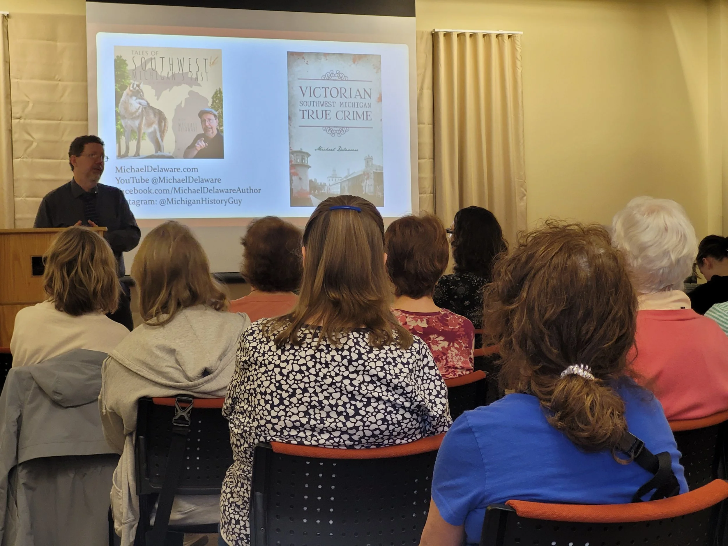 Author Michael Delaware giving a presentation in front of an audience at a local library.