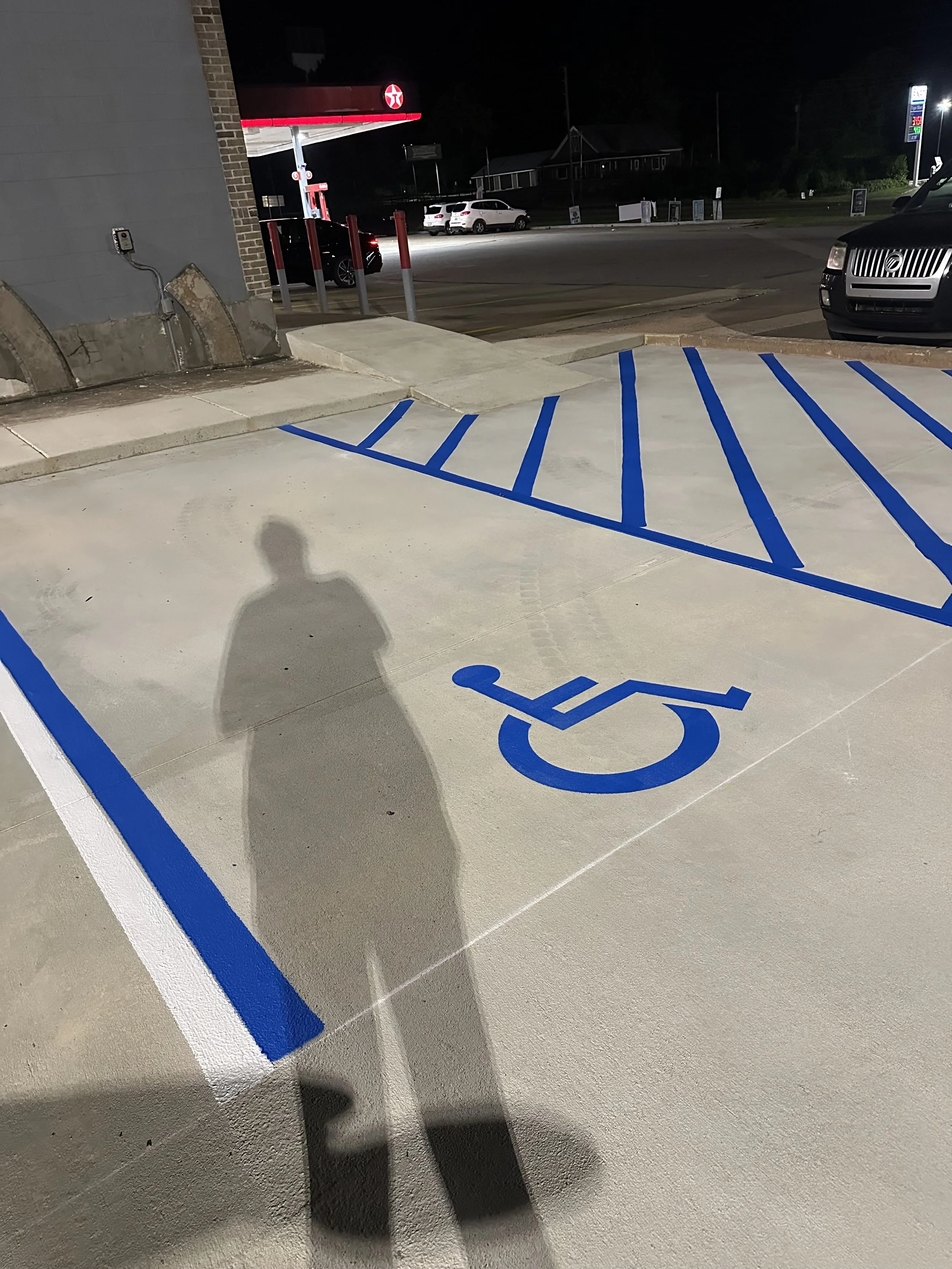 Gas station at night with blue handicap parking lines visible.