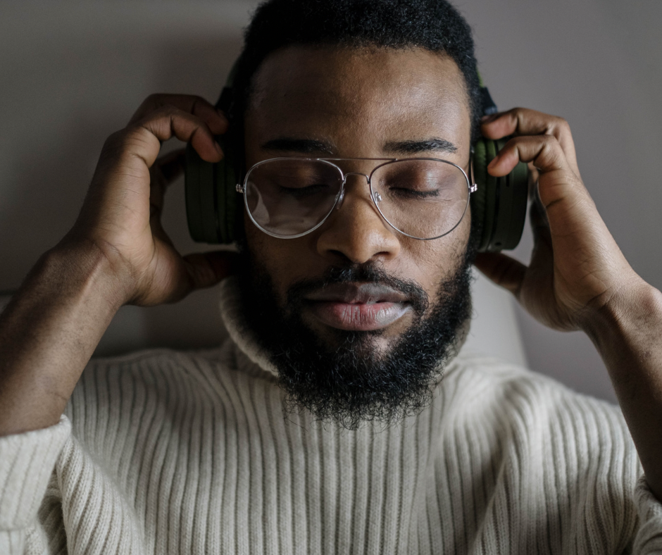 A man with glasses and a beard enjoying music with closed eyes while wearing headphones.